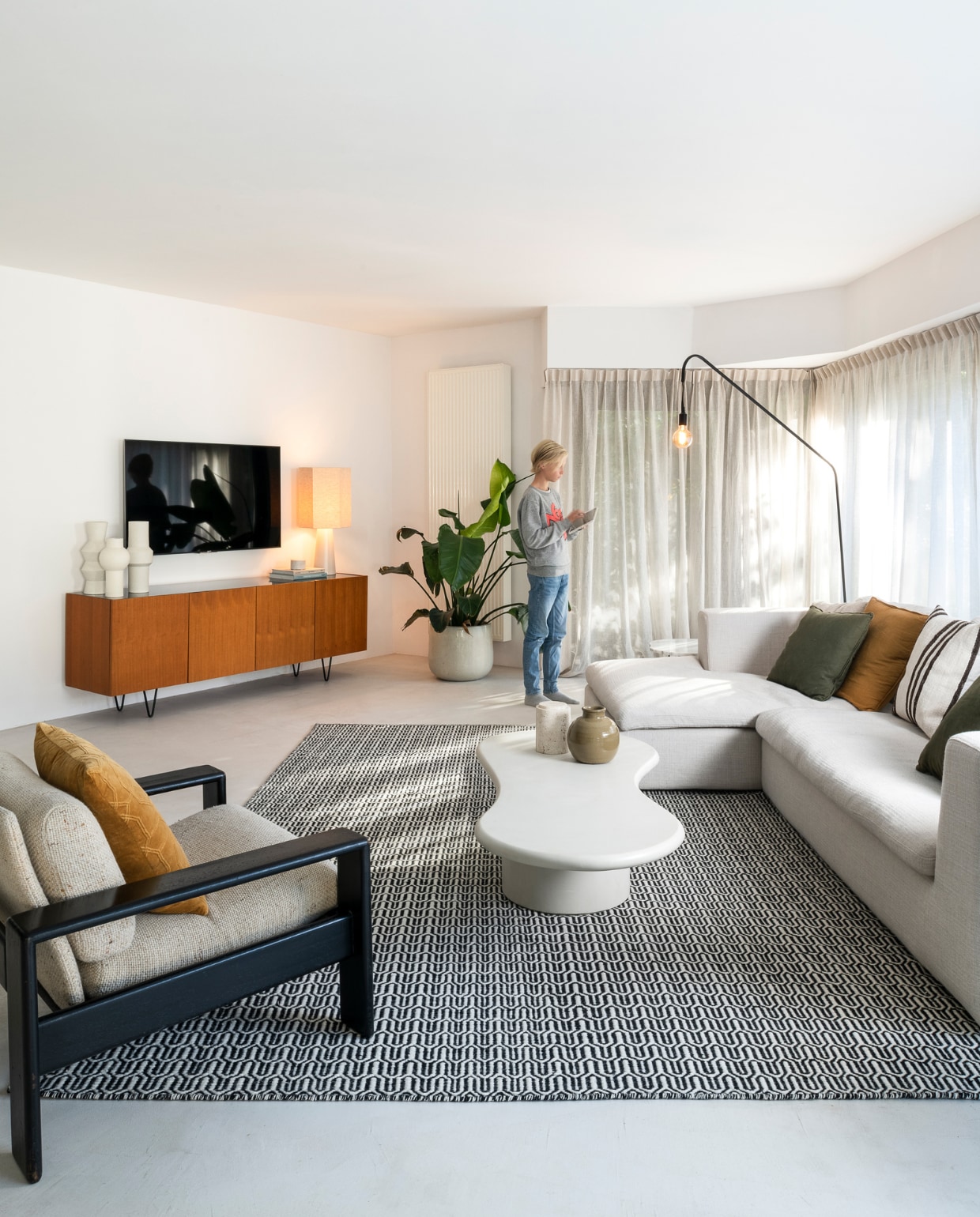 Hoekbank Modular, salontafel Orleans, vloerkleed Helder, dressoir Pisa en vloerlamp Ellis en vaas op salontafel van Furnified. Fauteuil vintage. Vazen op dressoir House Doctor, tafellamp HKliving. Kelimkussens Urban Nature Culture. Gordijnen Echt Gordijn. Overig onbekend. vtwonen 05-2023 | fotografie Jonah Samyn