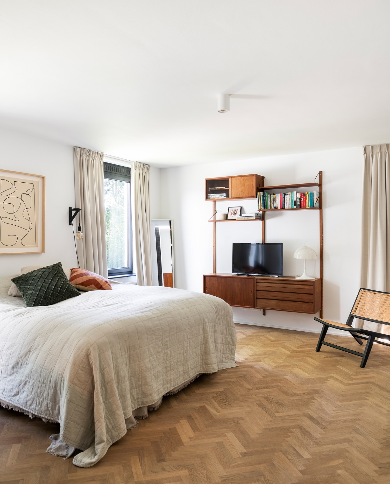 Vloer eiken visgraatparket van Floorhouse, bedsprei H&amp;M Home, kussens Chhatwal &amp; Jonsson, spiegel Ikea, kunstwerk Matt van Furnified, wandmeubel van Poul Cadovius vintage, tafellamp Panthella van Louis Poulsen. Overig onbekend. vtwonen 05-2023 | fotografie Jonah Samyn
