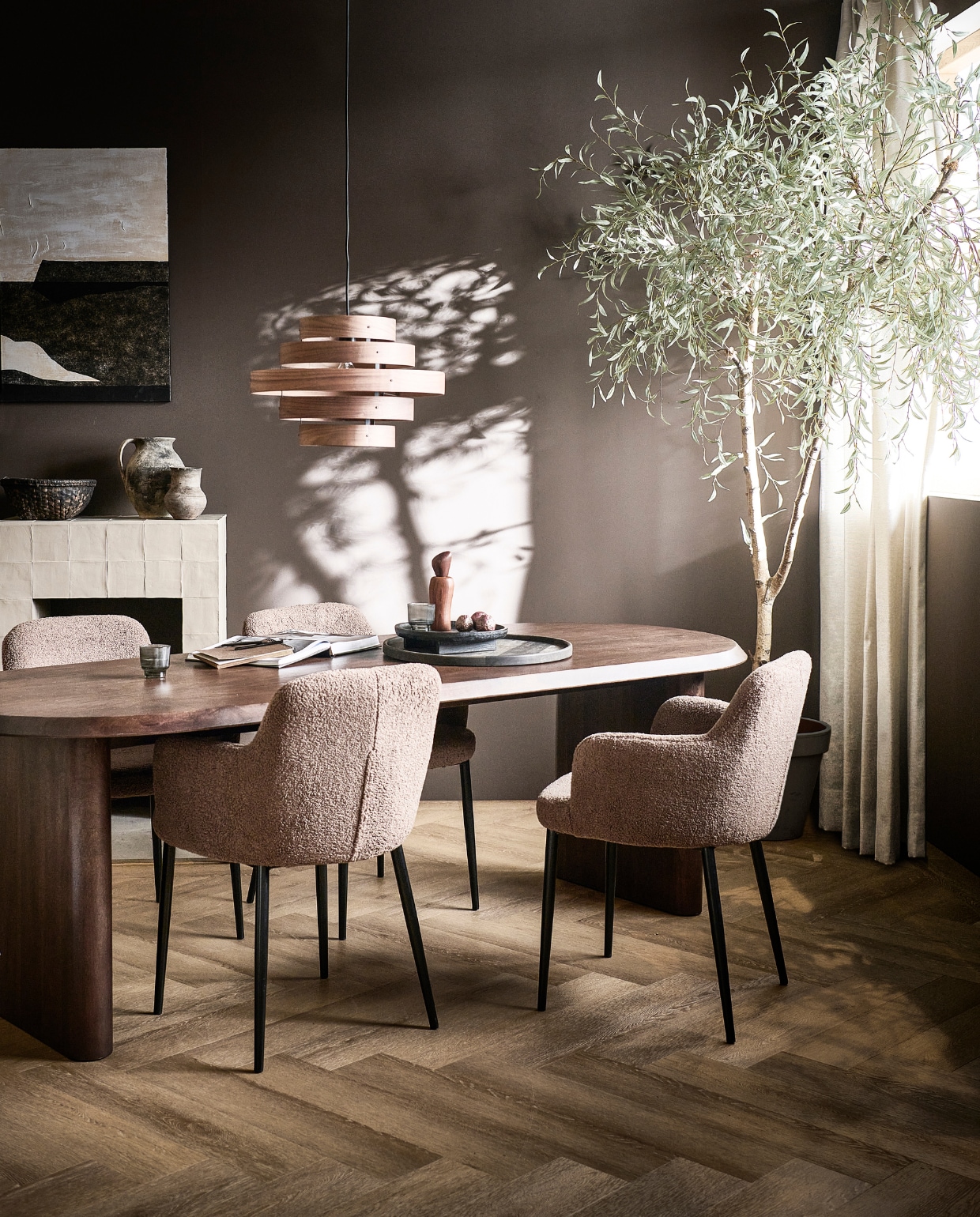 Walnootfineer eettafel Ellips, 180x90x75 cm (lxbxh) € 1299,-, ook in 240x90x75 cm (lxbxh), eetkamerstoelen Dining in taupe, teddystof en metaal, 62x53x81 cm (bxdxh) € 249,-, ook in teddystof off white.M.m.v. vtwonen.nl/shop (notenhouten hanglamp van ETH, schilderij van Kave Home, houten pepermolen van Ferm Living, mangohouten bord van vtwonen, vloerkleed van Bolia), hm.com (zwart houten dienblad), karwei.nl (muurverf Warmbruin van vtwonen, gordijn Drizzle in off white van vtwonen), vtwonen.nl (pvc-vloer Herringbone in Sun Kissed van vtwonen). Overig privébezit.