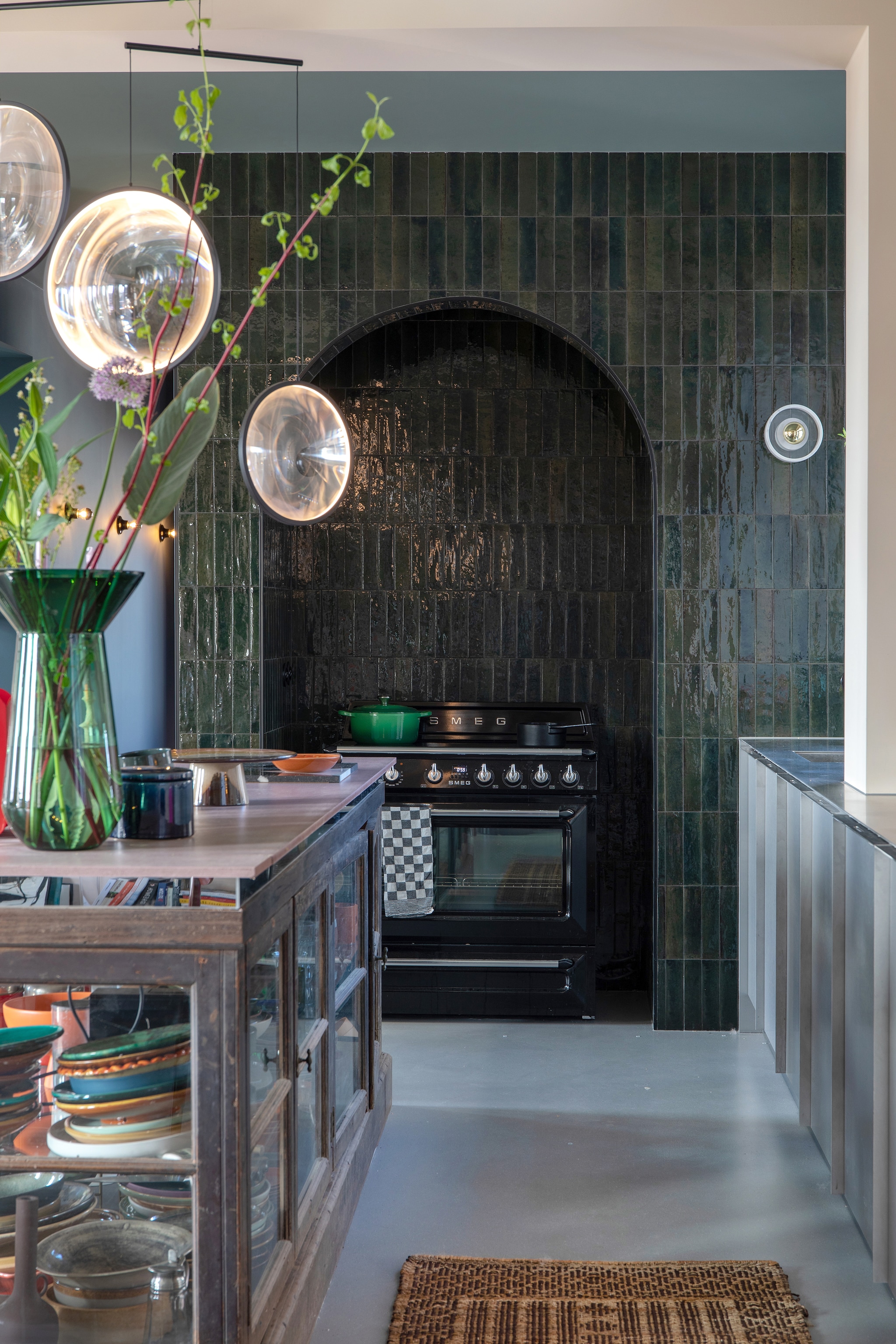 Wandtegels Olivia via Sanitairwinkel, fornuis Smeg, groene pan Le Creuset, zwarte steelpan Serax, theedoek Dok, aardewerken pot en vitrine vintage, hanglamp Dcw Editions, groene vaas Polspotten. vtwonen 05-2023 | styling &amp; fotografie Theo-Bert Pot &amp; Jelle van de Schoor