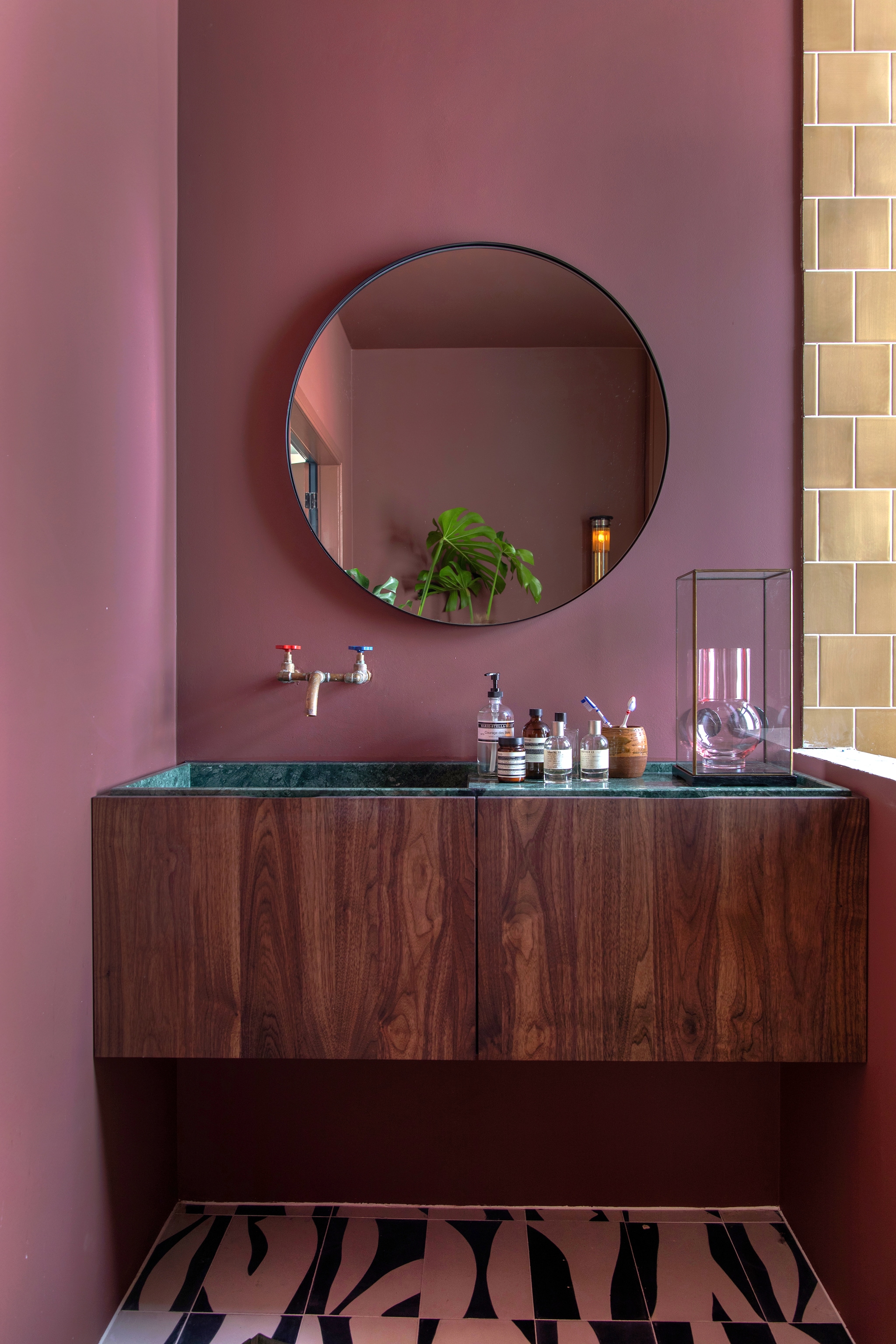Muurverf Full Plum van Flexa, spiegel Kwantum, beige wandtegels File Under Pop, vloertegels Popham Design via Rozetta. Badkamermeubel op maat gemaakt van hout en groen marmer Houtmerk. Wandkraan Koperenkranen, geuren en zeep van Marie-Stella-Maris, Aesop en Le Labo, vaas in stolp HKliving. vtwonen 05-2023 | styling &amp; fotografie Theo-Bert Pot &amp; Jelle van de Schoor