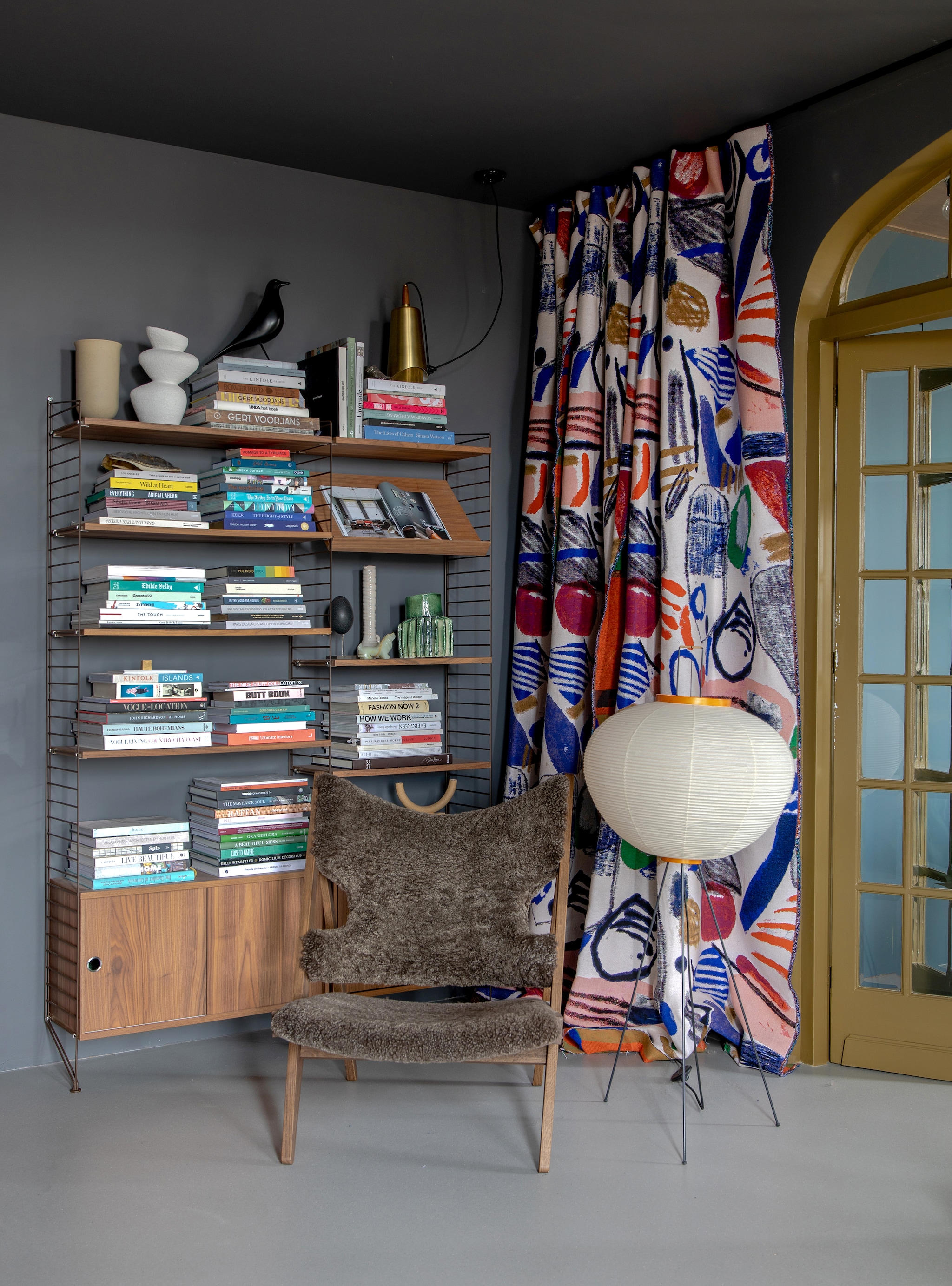 Muurverf 85% Grafiet en verf deur The Greenhouse 7 van Flexa. Kast String Furniture. Beige vaas, stoel en goudkleurige lamp Menu. Grijze vaas H&amp;M Home, vogel Vitra, zwart ei vintage, hoge vaas HKliving, groene vaas Floris Wubben. Vloerlamp Akari via Vitra, gordijnen Pierre Frey via Drent &amp; Van Dijk. vtwonen 05-2023 | styling &amp; fotografie Theo-Bert Pot &amp; Jelle van de Schoor
