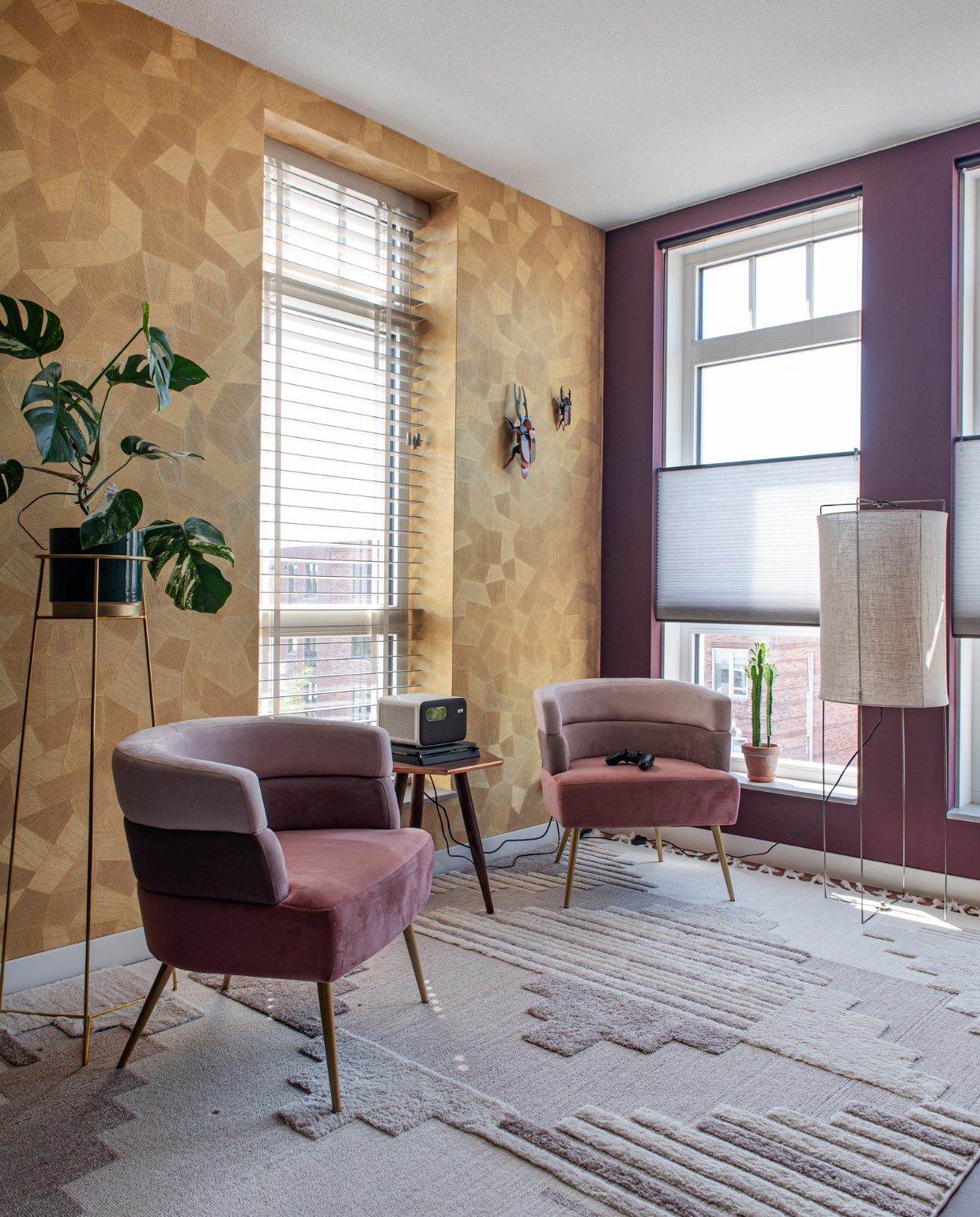 Behang Monsoon Facetin Pure Gold van Arte, wandinsecten Studio Roof, muurverf Brinjal van Farrow &amp; Ball, raambekleding Luxaflex. Plantenstandaard Loods 5. Fauteuils Sandwich in Mauve van Kare Design, bijzettafel Westwing, vloerkleed Oyo in Crème van Benuta. Vloerlamp Lamp en Licht. vtwonen 05-2023 | productie De Binnenkijkers | styling Jeske Weel | fotografie Caroline Coehorst