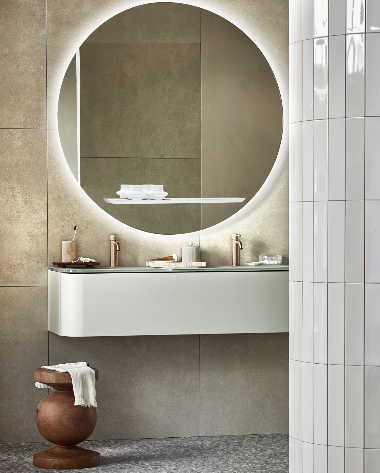 Spiegel Reflect, inclusief ledlicht en condensvrij, 120 cm (Ø), ook in 80 cm (Ø). Top solid onderkast Bend in Zand met push to open-systeem, 130x48x31 cm (bxdxh), ook in 31x90x48 cm. Vloer: vloer- en wandtegel Terrazzo Clay Flakes, 90x90 cm. Achterwand: vloer- en wandtegel Raw Sand Mat, 80x80 cm. Op de ronde wand: wandtegel Shapes Vapor glans, 7,5x30 cm. M.m.v. plieger.nl (wastafelkranen Roma), polspotten.nl (houten kruk), zarahome.com (travertin tandenborstelhouder, houten dienblad, travertin dienblad, pot met deksel, kwasten, kleine witte schaal, tube crème), hm.com (handdoek, badmat, glazen doosje). Overig privébezit. Beeld vtwonen 05-2023 | productie Tanja Saarberg | styling Sanne Ketelaar | fotografie Peggy Janssen