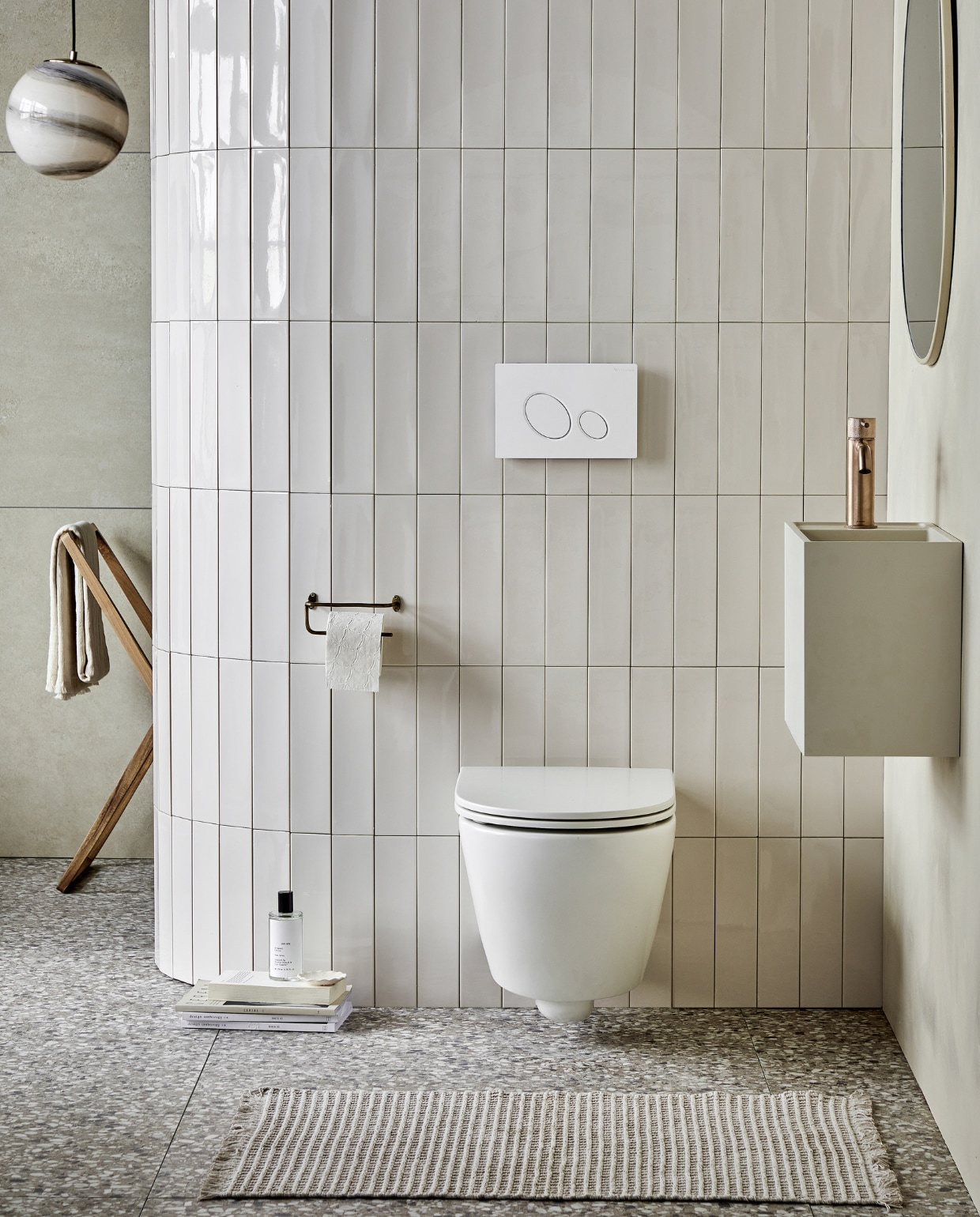 Keramieken toilet Bloc in Mat Wit, met soft close-zitting ( ), ook in matzwart en matzand. Top solid toiletwas-tafel Wide in zand, 40x30x22 cm (bxdxh) ( ) ook in grijs, wit en zand en in materialen marmer wit, bruin, zwart en zilvergrijs. Op de vloer: vloer- en wandtegel Terrazzo Clay Flakes, 90x90 cm, ( ). Op de afgeronde muur: wandtegel Shapes Vapor glans, 7,5x30 cm, ( ). Op de achterwand: vloer- en wandtegel Raw Sand Mat, 80x80 cm, ( ). M.m.v plieger.nl (wastafelkraan Roma), vtwonen.nl/shop (hanglamp van Bloomingville), zarahome.com (roomspray, houten wasrek, handdoek, messing toiletrolhouder, ronde spiegel), hm.com (badmat). Overig privébezit. Beeld vtwonen 05-2023 | productie Tanja Saarberg | styling Sanne Ketelaar | fotografie Peggy Janssen