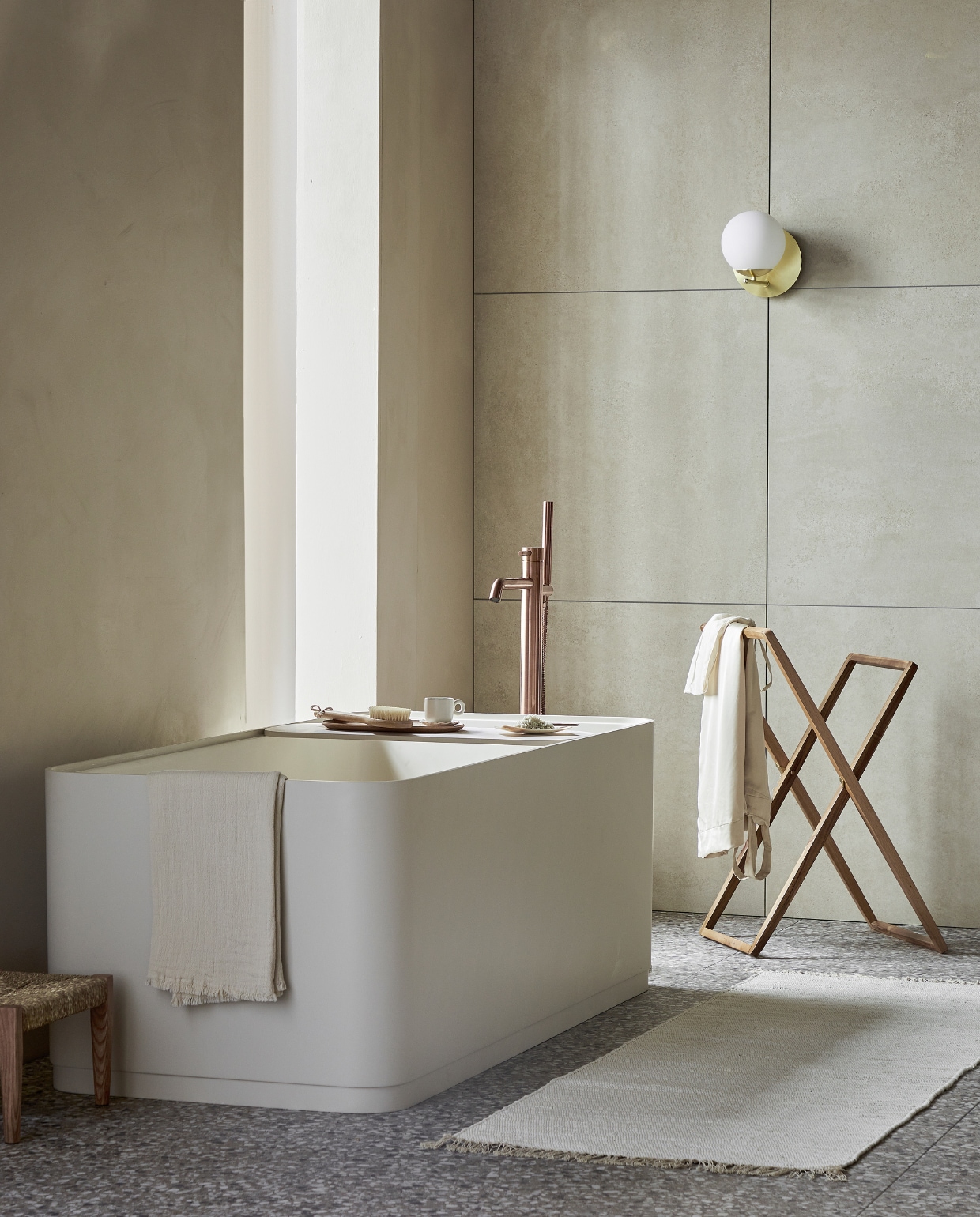 Top solid bad Soft Edge in zand inclusief plateau, 160x73x59,5 cm (lxbxh), 200 liter, ook in wit, grijs en zwart. Vloer: vloer- en wandtegel Terrazzo Clay Flakes, 90x90 cm. Achterwand: vloer- en wandtegel Raw Sand Mat, 80x80 cm. M.m.v. plieger.nl (badkraan Roma), vestingh.nl (muurverf Ibiza Rush van Lab Paint), vtwonen.nl/shop (wandlamp van Trio), zarahome.com (kledingrek, dienblad, zeepschaaltje, kruk), dille-kamille.nl (wasborstel, badzout), hm.com (handdoek, badmat, kopje). Overig privébezit. Beeld vtwonen 05-2023 | productie Tanja Saarberg | styling Sanne Ketelaar | fotografie Peggy Janssen