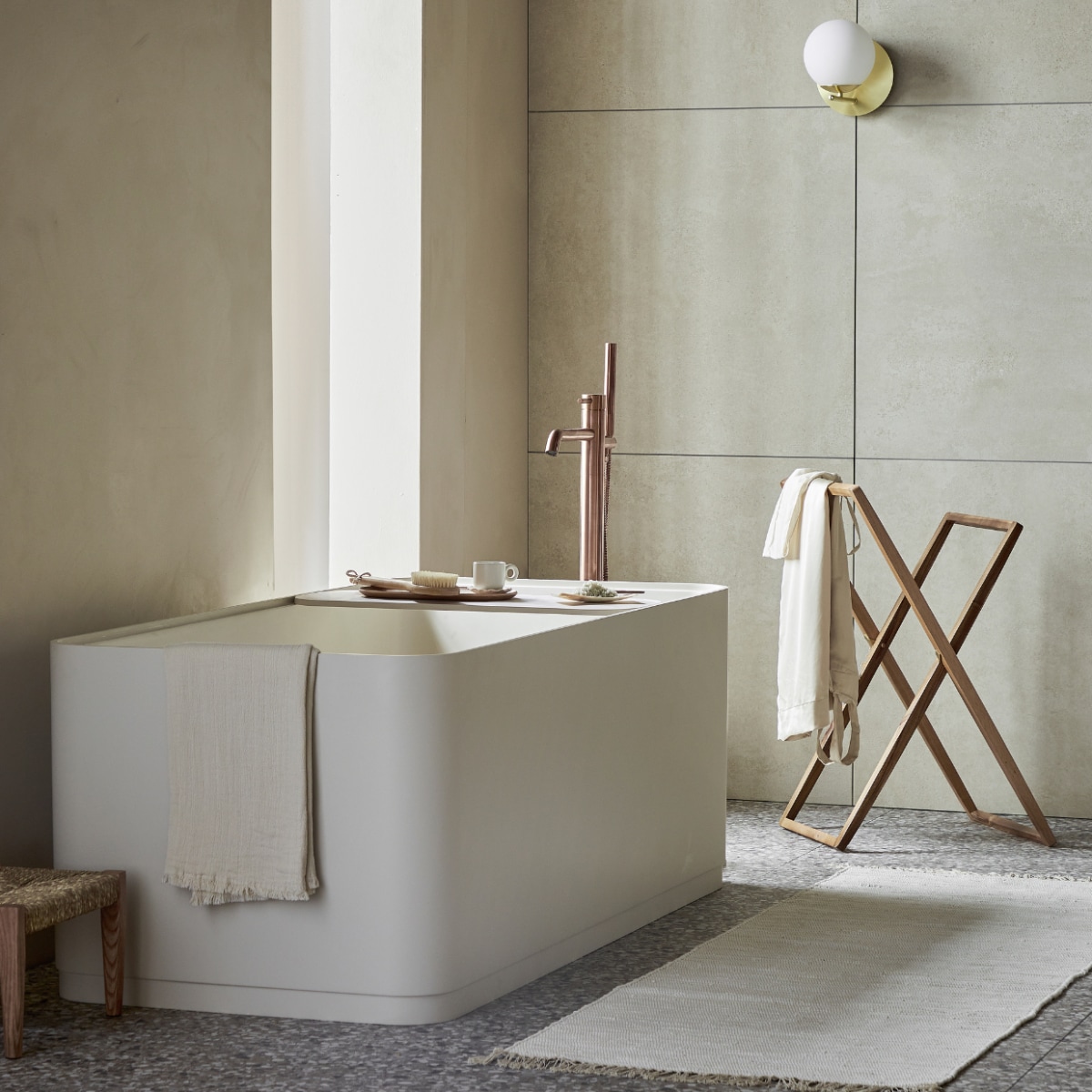 Top solid bad Soft Edge in zand inclusief plateau, 160x73x59,5 cm (lxbxh), 200 liter, ook in wit, grijs en zwart. Vloer: vloer- en wandtegel Terrazzo Clay Flakes, 90x90 cm. Achterwand: vloer- en wandtegel Raw Sand Mat, 80x80 cm. M.m.v. plieger.nl (badkraan Roma), vestingh.nl (muurverf Ibiza Rush van Lab Paint), vtwonen.nl/shop (wandlamp van Trio), zarahome.com (kledingrek, dienblad, zeepschaaltje, kruk), dille-kamille.nl (wasborstel, badzout), hm.com (handdoek, badmat, kopje). Overig privbezit. Beeld vtwonen 05-2023 | productie Tanja Saarberg | styling Sanne Ketelaar | fotografie Peggy Janssen