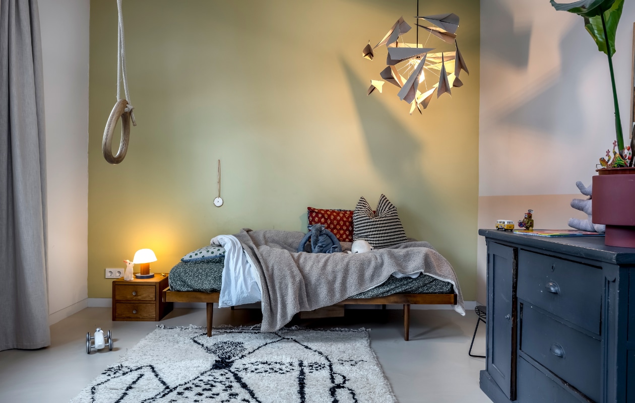 Bed en grote kast Marktplaats. Kussens Atelier Pomme. Nachtkastje erfstuk. Hanglamp zelfgemaakt, tafellamp &amp;Klevering. Schommel Lillagunga, kinderstoel KidsDepot. Vloerkleed Sofia Rugs Art via Etsy. Linnen gordijnen De Stoffenkraam. Groene muurverf F9.20.70. witte muurverf FN.01.81 en muurverf onderste rand lambrisering E1.12.76 van Sikkens. Overig onbekend. vtwonen 05-2023 | fotografie Henny van Belkom