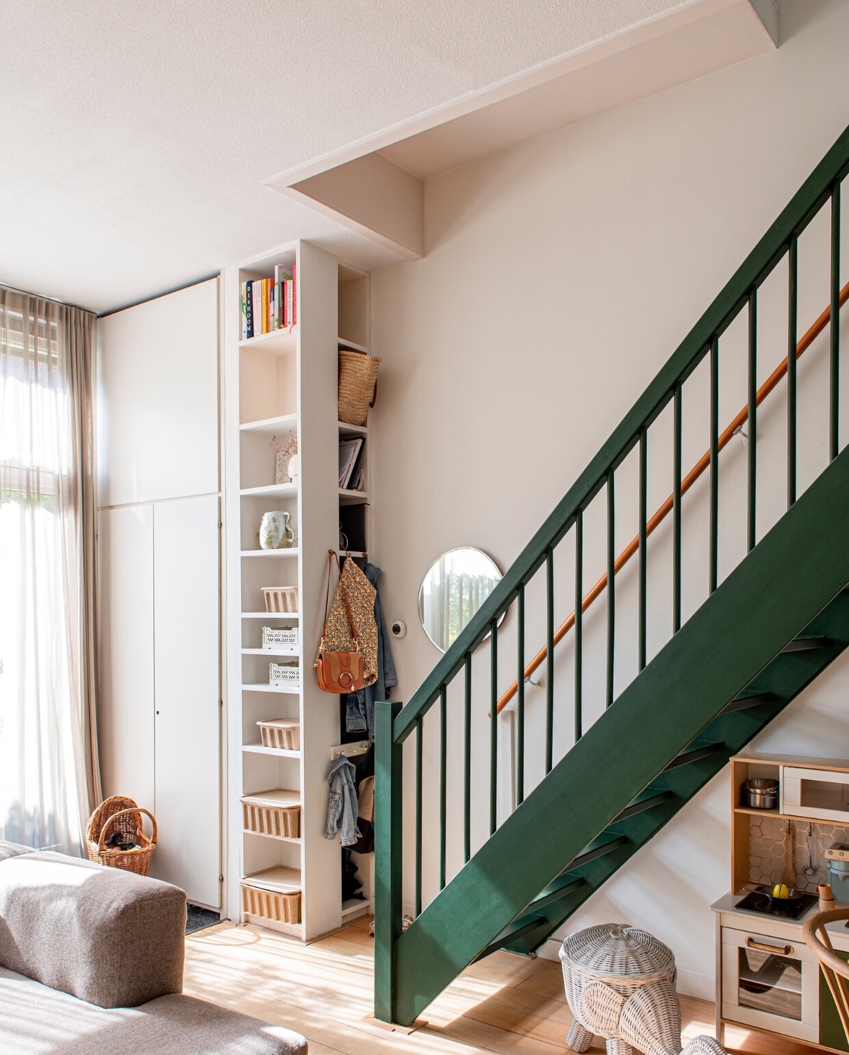 Verfkleur trap Duck Green van Farrow &amp; Ball. Bank Hay. Ronde spiegel en manden in kast Ferm Living. Poppenwagen familiestuk. Overig onbekend. vtwonen binnenkijken special 131-2023 | fotografie Caroline Coehorst
