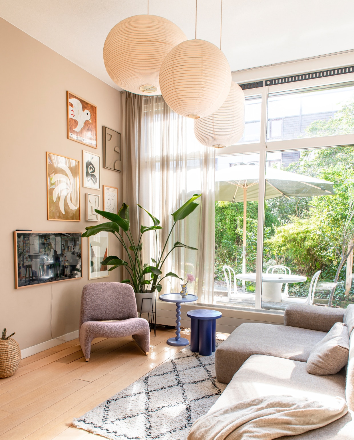 Muurverf Jitney van Farrow &amp; Ball. Bank en hanglampen Hay. Plaid H&amp;M Home. Vloerkleed Karwei. Vintage fauteuil Alky van Artifort via Morentz. Hoge bijzettafel Polspotten, lage Noo.ma. Tv Samsung. Kunst aan de muur o.a. Fly To Tokyo van Mogu Takahashi, Edith Beurskens en Enkel Art. Plantenbak Fonq. Rieten mand Hema. Tafel en stoelen buiten Loods 5. vtwonen binnenkijken special 131-2023 | fotografie Caroline Coehorst