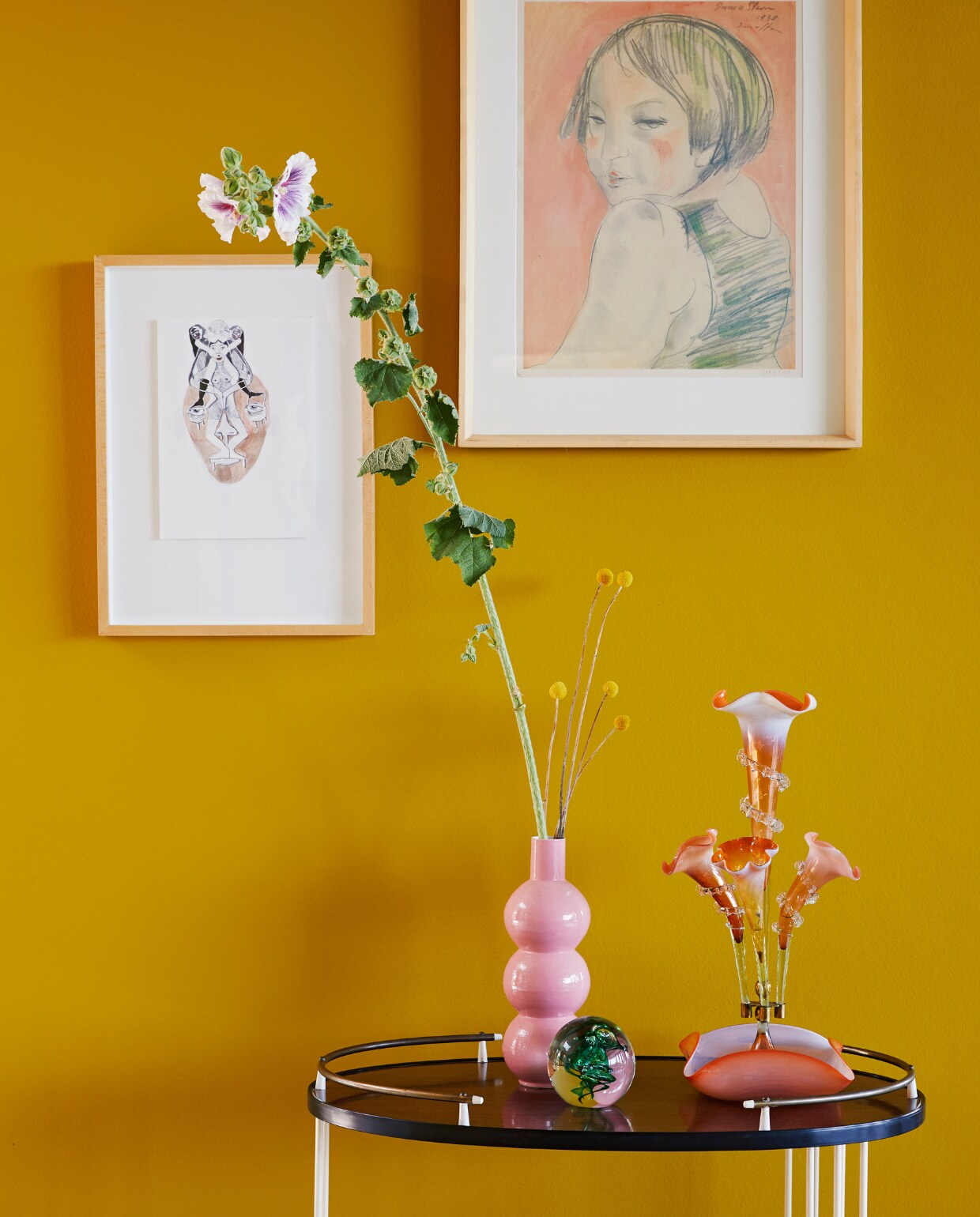 Vergelijkbare muurverf 100% Duinpan van Flexa. Vintage drankentrolley Re-Trend. Portret rechts Irma Stern. Roze vaas vintage, glazen bol David Reade en glazen epergne antiek. Overig onbekend. vtwonen special binnenkijken 06-2022 | productie BUREAUX | styling Sven Alberding | fotografie Elsa Young