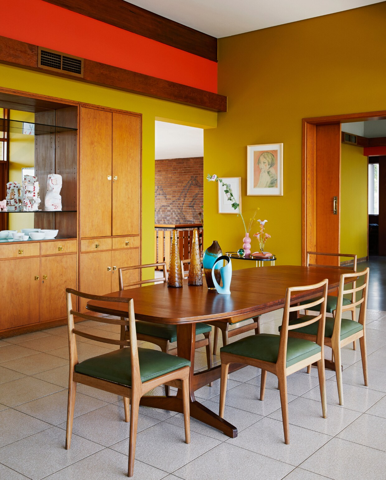 Het houtwerk in de eetkamer is origineel en door Lezanne en Walter opgeknapt. Vergelijkbare muurverf 100% Duinpan van Flexa. Eethoek vintage Deens design. Ingelijst portret Irma Stern. vtwonen special binnenkijken 06-2022 | productie BUREAUX | styling Sven Alberding | fotografie Elsa Young