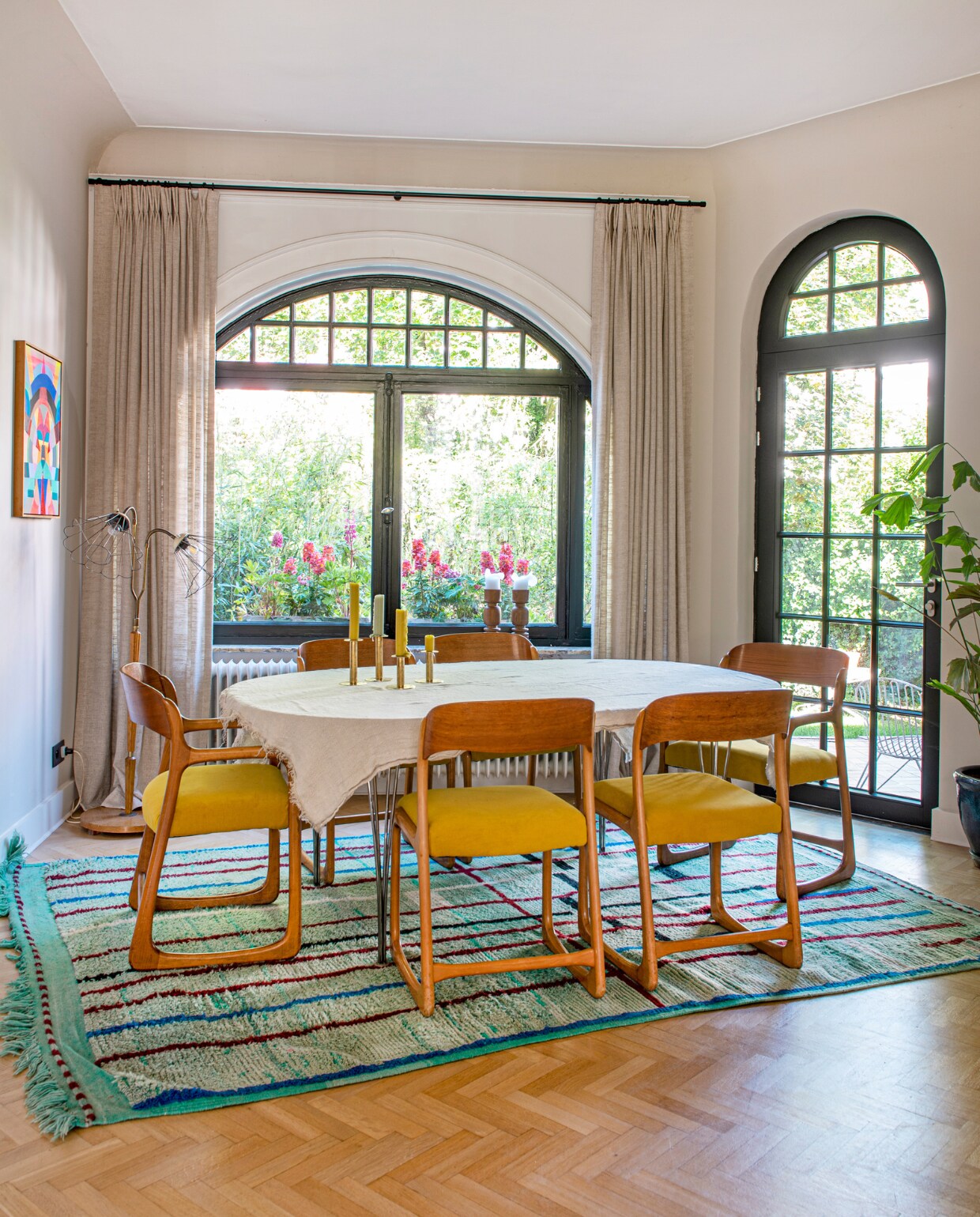 De parketvloer lag al in het huis. Stoelen Baumann vintage. Tafel Fritz Hansen. Tafelkleed en gordijnen Bruder. Kandelaars Labotika. Vloerkleed Soufiane Zarib. Lamp rommelmarkt. Kunstwerk Maya Hayuk. vtwonen special binnenkijken 131-2023 | fotografie Caroline Coehorst