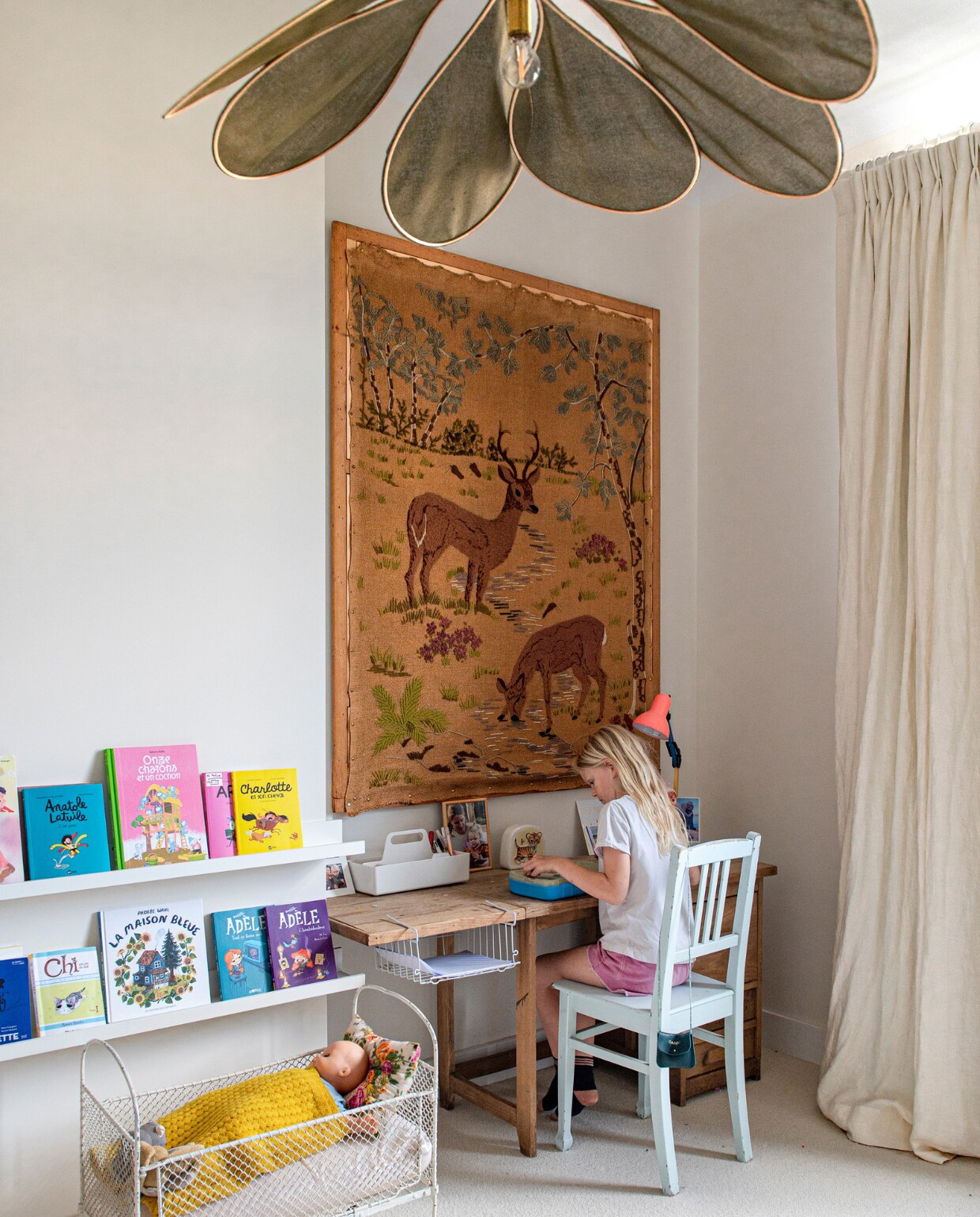 Verfkleur Crème Café van Ressource Peintures. Boekenplanken Ikea. Poppenbed, wanddecoratie, stoel en witte Vitra-opbergbak tweedehands. Hanglamp cadeau. Bureau uit Sandrines kindertijd. Gordijnen Bruder. vtwonen special binnenkijken 131-2023 | fotografie Caroline Coehorst