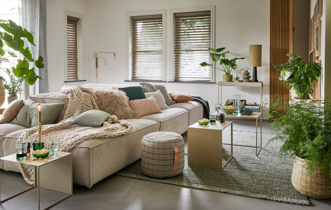 Ecru elementenbank Square van Easy Sofa, per module vanaf _ 605,- (hoekbankxxl.nl). Groen geweven vloerkleed Versanti van Linie Design, 240x170 cm _ 440,- (vtwonen.nl). Ecru metalen bijzettafel Cluster van Ferm Living, set van 3 _ 380,-, grijze geruite poef Grid van Oyoy, 40x38 cm (_xh) _ 104,55, groene kristalglazen kandelaar Parker, 8x3x8 cm _ 24,65 (wonenmetlef.nl). Cr_mekleurige gebreide plaid, 152x127 cm _ 149,- (noirhome.nl). Kussens van links naar rechts: lichtbruin kussen met visgraatmotief Kata van Oyoy, 40x60 cm _ 57,80 (wonenmetlef.nl), linnen kussen Olive, 40x60 cm _ 59,- (bymolle.com), kussen Nordic Knit van Marc O_Polo, 30x60 cm _ 39,99 (vtwonen.nl), schapenvachtkussen, 40x40 cm _ 69,- (noirhome.nl), groen gebreid kussen Solid van Malagoon, 50x50 cm _ 49,99 (vtwonen.nl), linnen kussen Blush, 35x50 cm _ 49,-, gerecycled gebreid denim kussen Sand, 40x60 cm _ 79,-, linnen kussen Olive, 60x60 cm _ 69,-, linnen kussen Cinnamon, 40x60 cm _ 59,- (bymolle.com). Donkergroene merinowollen deken van McNutt, 200x145 cm _ 100,-, groen glas van Serax, medium _ 9,50, groene glazen popcornschaaltjes Emeralds, 12,5 cm (_), per stuk _ 12,10, groen aardewerken chipsschaaltje Miscellaneous _ 7,- (vanmanenaantafel.nl). Gerecycled wijnglas Oli van Ferm Living _ 25,-, gerecyclede glazen karaf Oli Jug van Ferm Living _ 39,-, groene kaars Dryp van Ferm Living, per 2 _ 11,-, metalen plantenbak op poten Two Tier van Ferm Living, 25x75x80 cm _ 299,-, fotolijsten aan rechter wand, vanaf _ 35,- (byjensen.nl). Plant Philodendron, groot _ 149,95, bamboe mand _ 200,-, op side table plant Philodendron _ 22,50, groene metalen pot _ 35,-, plant rechts Monstera _ 28,95, plant voor Asparagus _ 44,95, bamboe mand _ 89,- (stadstuindebloemenpoort.nl). Messing wandlamp Swing van House Doctor, 65x35 cm _ 199,-, mosgroene keramieken vaas Eminent Circles, medium _ 49,99, keramieken tafellamp Stoneware met lampenkap van HKliving _ 209,-(vtwonen.nl). Terracotta bloempot Rosa, 12 cm (_ ) _ 9,50 (bymolle.com). Lichtbruin aardewerken suikerschaaltje Hagi van Oyoy (wonenmetlef.nl). Overig priv_bezit. vtwonen 02-2023 | styling Femke Pastijn | fotografie Peggy Janssen | assistentie Alex Lebbink