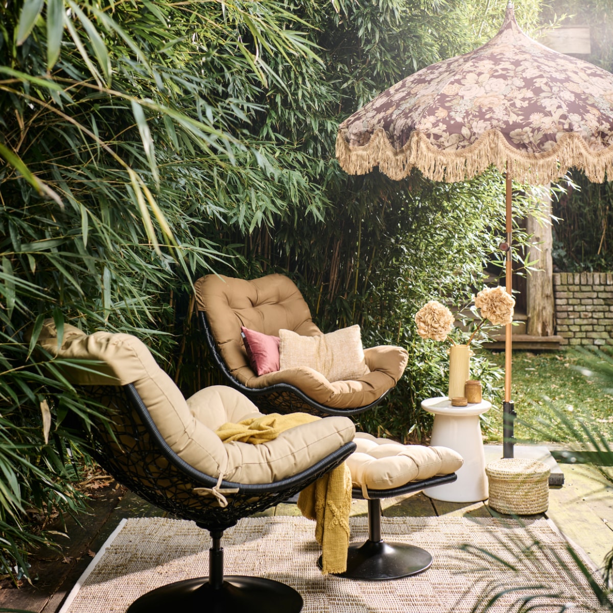 Rotan draaifauteuil Vive van Woood, met zitkussen, 82x105x100 cm (bxdxh), witte keramieken bijzettafel Button van vtwonen, 35x45 cm (Øxh) (vtwonen.nl/shop). Rotan hocker Vive van Woood (basiclabel.nl). Stoffen parasol uit collectie van Marie Olsson Nylander (hkliving.com). Rieten mand, prijs op aanvraag (com-anders.nl). Gele keramieken vaas, geel geweven kussen, 30x50 cm, gele geweven plaid (urbannatureculture.com). Roze fluwelen kussen, 30x50 cm (hetkabinet.nl). Houten pot met deksel (jolandelijk.nl). Geweven vloerkleed van Madam Stoltz, 120x180 cm (deens.nl). Overig privébezit. vtwonen 05-2023 | styling Marlies Does | fotografie Sjoerd Eickmans