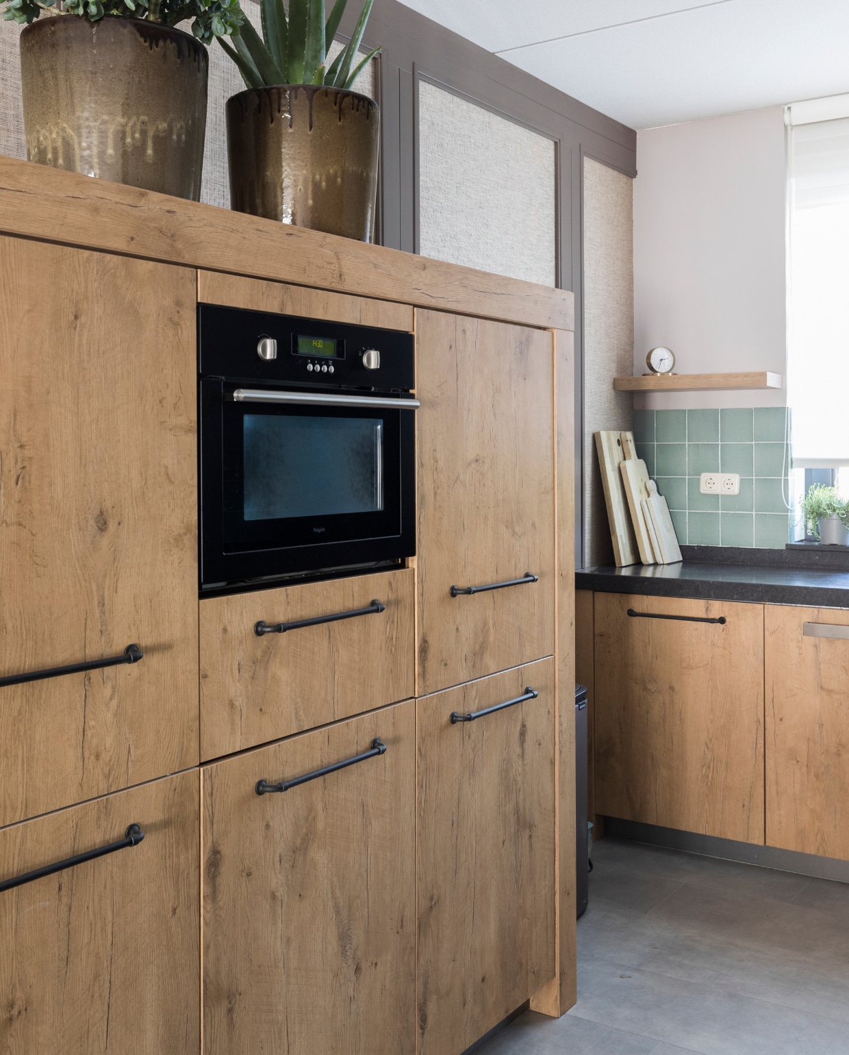 Houten keuken, stalen zwarte handgrepen, keukenblad, zeegroene tegels, snijplanken, bloempotten vtwonen 06-2021 | wvojh seizoen 14 aflevering 7 | styling Marianne Luning | fotografie Margriet Hoekstra