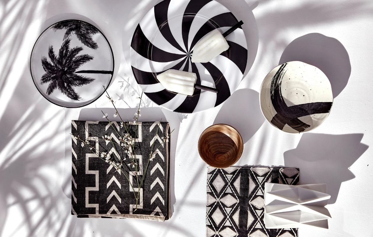 Kussenhoes € 24,95 (mrsbloom.nl). Schaal met kruis, set van 4 € 33,56, ontbijtbord met palmboom, 22 cm (Ø) € 9,95 (hkliving.com). Stof Sojourn-Domino van Pollack, per meter € 246,- (ateliersem.nl). Geometrische kandelaar, 10x14 cm (Øxh) € 17,95, bord met zwart-witte strepen Hypnotise Mesmerise van House Of Rym, 25 cm (Ø) € 22,50 (livvlifestyle.nl). Houten kom € 12,95 (householdhardware.nl). vtwonen 06-2023 | styling Kim Timmerman | fotografie Peggy Janssen