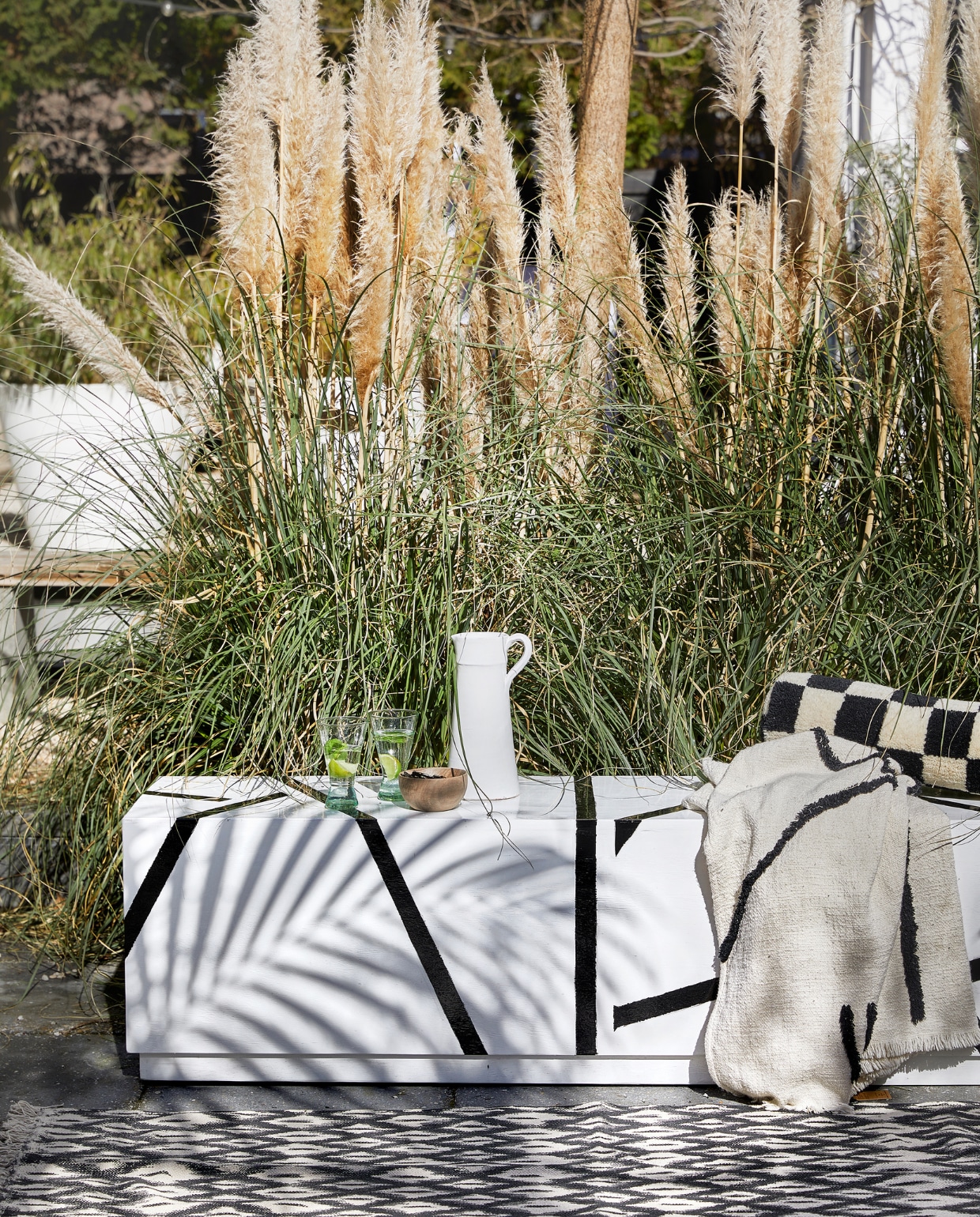 Bank op maat gemaakt, prijs op aanvraag (com-anders.nl). Witte karaf € 45,-, gerecyclede glazen € 6,-, houten kom € 12,95 (householdhardware.nl). Plaid Lines, 130x170 cm € 75,-, rolkussen, 13x50 (Øxl) € 79,- (hkliving.com). Vloerkleed € 89,95 (mrsbloom.nl). vtwonen 06-2023 | styling Kim Timmerman | fotografie Peggy Janssen