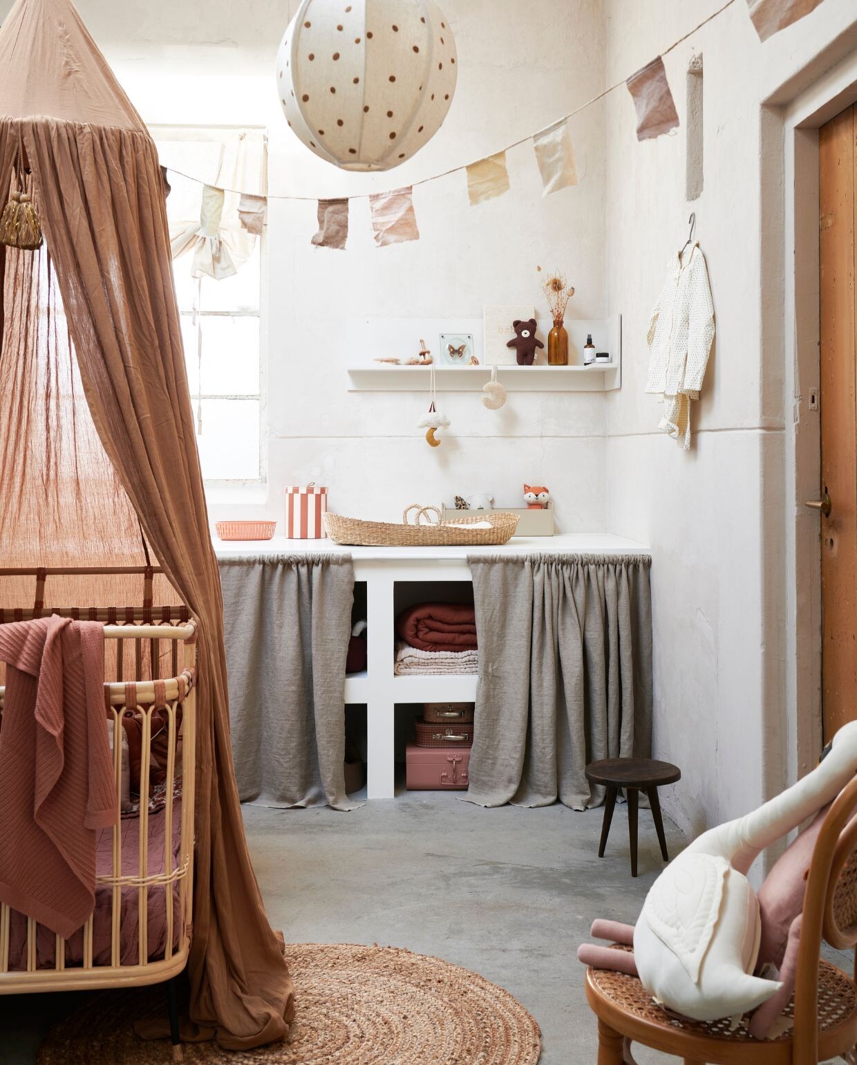 Bed Children’s bed Frederick van Bermbach Handcrafted, deken Diamond Deep Clay van Camomile London, gebloemde plaid Antoinette Cream Bohemian Flowers van Louise Misha, donkerbruine knuffelbeer Bernard van Bonton, knuffel vos Renard Tissu van Bonton, metalen ovale opbergmand in kleur Roest van Hay, ronde gestreepte opbergmand van Oyoy Living Design, set van 3, muziekmobile Moon &amp; Star van Konges Sløjd, beige metalen opbergbox van Ferm Living, houten borstel in vorm van schelp van Konges Sløjd, set van 3, bedhemel in kleur Almond van Konges Sløjd, gevlochten opbergmand appelvorm van Ferm Livin, roze koffer van Bonton, set koffers met print van Oyoy Living Design, knuffel paard in Dusty Rose van Ferm Living, witte pyjama Dot van Studio Feder, gebreid roze dekentje Akira Brick van Hvid, dekens in de kast: lichtroze Mellow Tawny Blanket van Garbo &amp; Friends vanaf, Cinnamon Muslin Filled Quilt van Garbo &amp; Friends (storeofdaydreams.com). Lichtbeige rolgordijn (hm.com). Hanglamp Dots Textile van Ferm Living (coulourlocale.eu). Juten vloerkleed van Kave Home, 100 cm (Ø) (vtwonen.nl). Zeegras verschoonmand van Cam Cam, knuffel zwaan Vicky Swan van Numero 74 (lidor.nl). Speendoek in de vorm van maan van Dappermaentje (psikhouvanjou.nl). Babyverzorging van Alma, houten rammelaar, babybook  (zoenvoorgust.com). Siliconen badthermometer muis, beige kam met schildpadmotief (zarahome.com). Gordijnen voor de kast zelfgemaakt van effen linnen, per strekkende meter (kniphal.nl). Fopspeen kers (dekleineparade.com). Wandplank zelfgemaakt. Vorkheftruck van Goki (lanoeka.com). Oude leren koffers vanaf (burbri.nl). Stoel Malawi Kids Chair van People of the Sun (archive-store.nl). Overig privébezit. vtwonen 2021-13 kids bijlage | styling Kim van Rossenberg | fotografie Sjoerd Eickmans