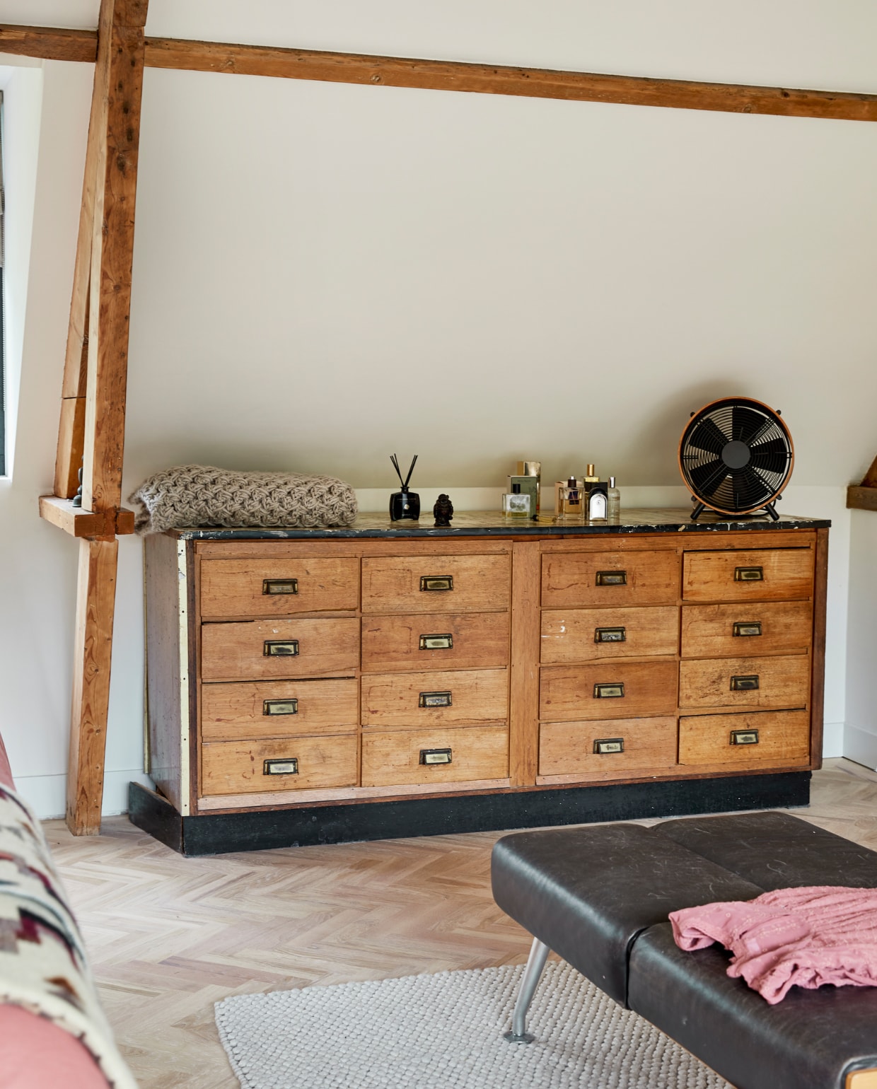 Kast met laden vintage, ventilator Anno Design, parfum Retreat, sprei zelf gehaakt. Houten vloer Balkan Wood, vloerkleed Hay, bank herkomst onbekend, kleding Zara. vtwonen 05-2021 | fotografie Peggy Janssen