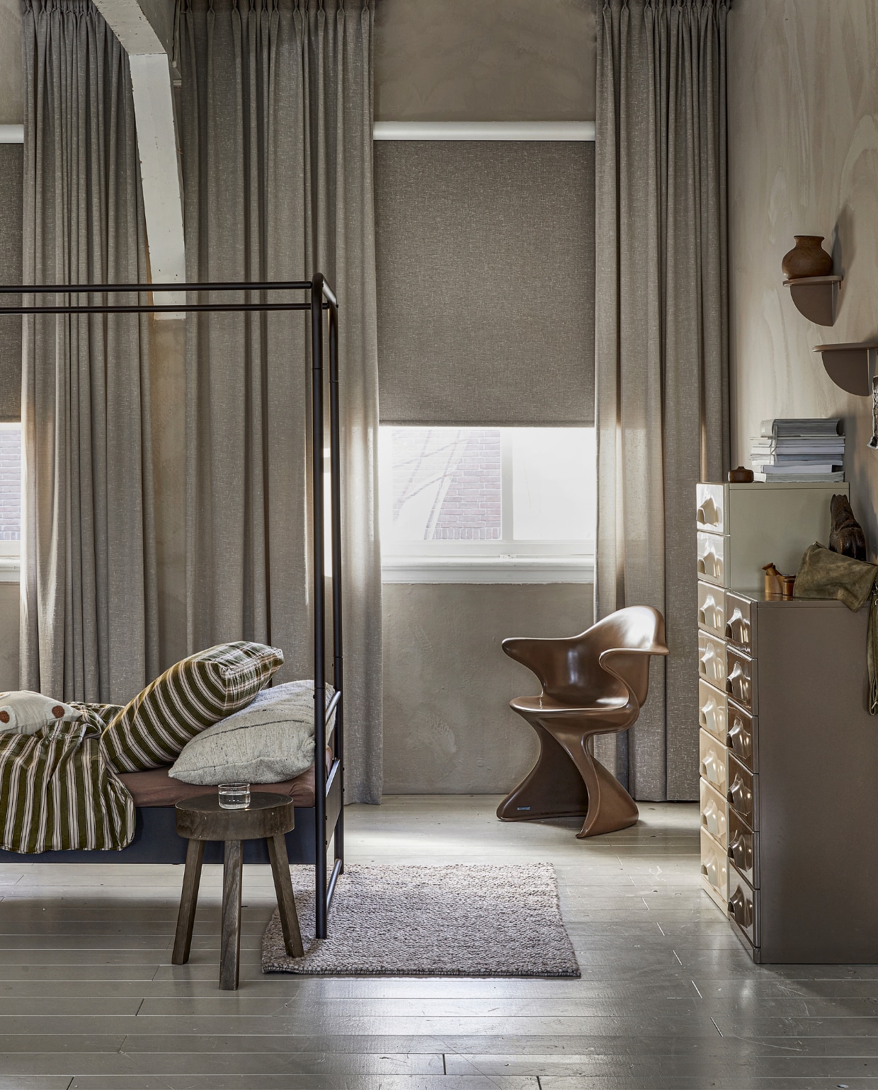 Lichtdoorlatend gordijn op maat, met dubbele plooi in stof Grain (1772) kleur Kiezel vanaf € 26,99 per strekkende meter. Verduisterend rolgordijn op maat in kleur bruin slub (18007) vanaf € 110,50. M.m.v.: hkliving.nl (eetkamerstoel Sedia moka, retro ladenkasten), hm.com (vloerkleed, wandplanken, houten doosje), beddinghouse.nl (dekbedovertrek Pyjamas), basiclabel.nl (bijzettafel Sef, bedframe Bunk), rawmaterials.eu (beeldje Nandi XL, bruine vaas), pure-original.com (kalk muurverf Fresco in kleur Canvas), vtwonen.nl/shop (kussen met stippen van vtwonen, lakverf vloer kleur Flax). vtwonen 06-2023 | productie Tanja Saarberg | styling Marit Saladini Platjouw | fotografie Peggy Janssen