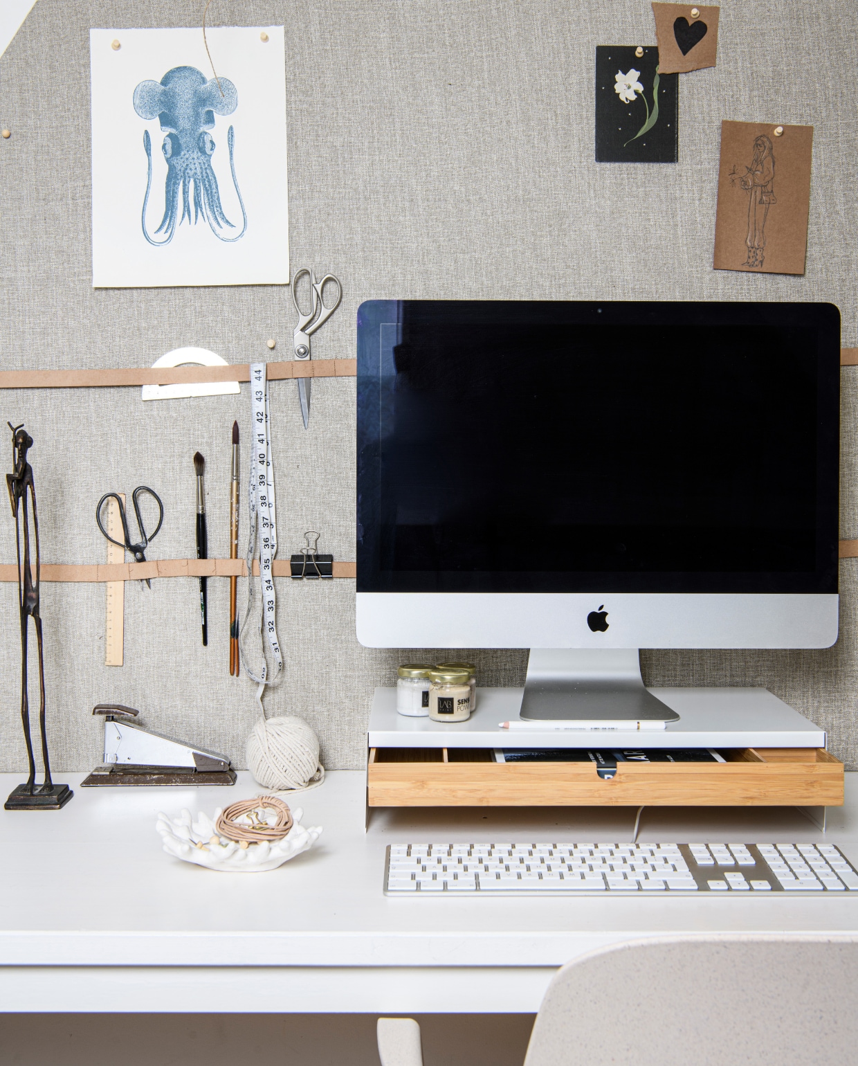 Van links naar rechts: wit/beige bureaustoel Odger, € 67,96 (Ikea.com). Op prikboard: beukenhouten liniaal, 30 cm € 3,95, rvs schaar € 12,95 (dille-kamille.nl) schaar. Kwasten, meetlint, clip en tekeningen (privébezit). Halfrond cirkel mal € 2,10 (sostrenegrene.com/nl). Op bureaublad: beeldjes gietijzer, verfpotjes (privébezit). Vintage nietmachine (kringloop). Schaaltje koraal € 8,40, leren koord € 2,63 (sostrenegrene.com/nl). Desktop monitor Mac (apple.com). Witte monitorstandaard Elloven met lade, 47x26x10 cm € 24,99 (ikea.com), boek Aarden, Ruth Allen € 25,99 (dille-kamille.nl). Styling Marit Saladini | Fotografie Louis Lemaire | Assistentie Rosa van Schie, Kiki de Koning