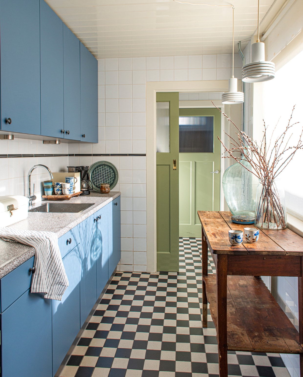 De keuken zat al in het huis. Vloertegels Mosa. Hanglampen, tafel en bolvaas tweedehands. Chinese kopjes en broodtrommel familiestukken. Mokken HKliving. vtwonen binnenkijken special 03-2023 | productie De Binnenkijkers | styling Jeske Weel | fotografie Caroline Coehorst