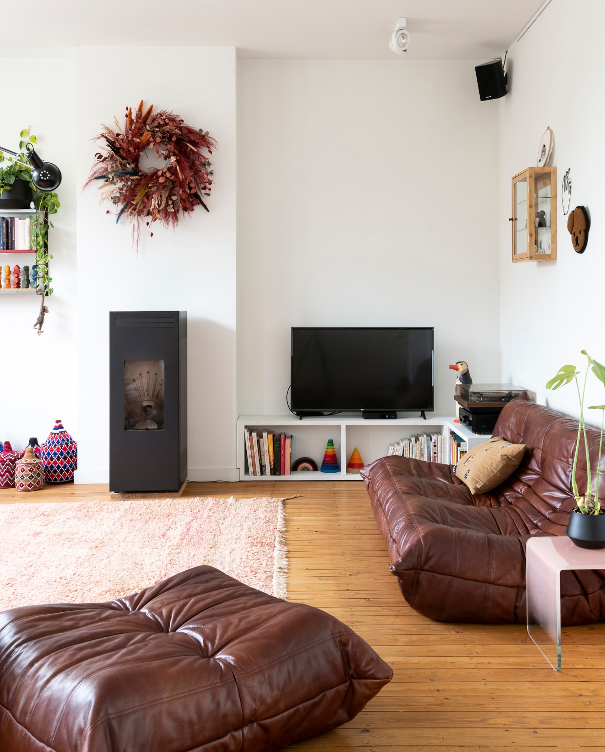 Zitelementen Togo van Ligne Roset, kussen Ferm Living, pelletkachel CMG, vloerkleed Maghribi Mood. Vintage wandrek Tomado, kleurige manden Petit Maroc, tv-meubel zelfgemaakt. Speelgoed van Grimm’s, PlanToys en Dëna. Bijzettafel Made, vitrinekast Jysk, wandkleed hond Maison Deux, krans Anne Engels, pinguïnlamp Heico. Vloer (originele) grenen planken met kleurloze olie. vtwonen 06-2023 | styling &amp; fotografie Jonah Samyn