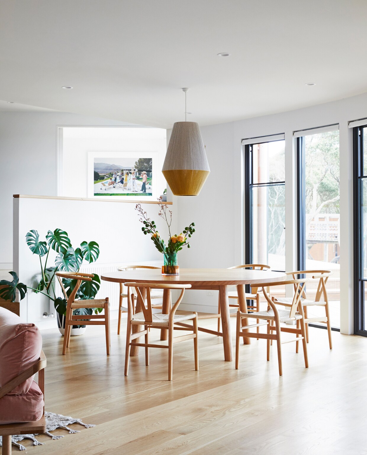 Hanglamp en eettafel Pop and Scott. Stoelen CH24 Wishbone Coastal Living Sorrento. Kunstwerk Desert Houseparty van Slim Aarons. vtwonen special binnenkijken 07-2022 | productie Living Inside | styling Julia Green | fotografie Armelle Habib