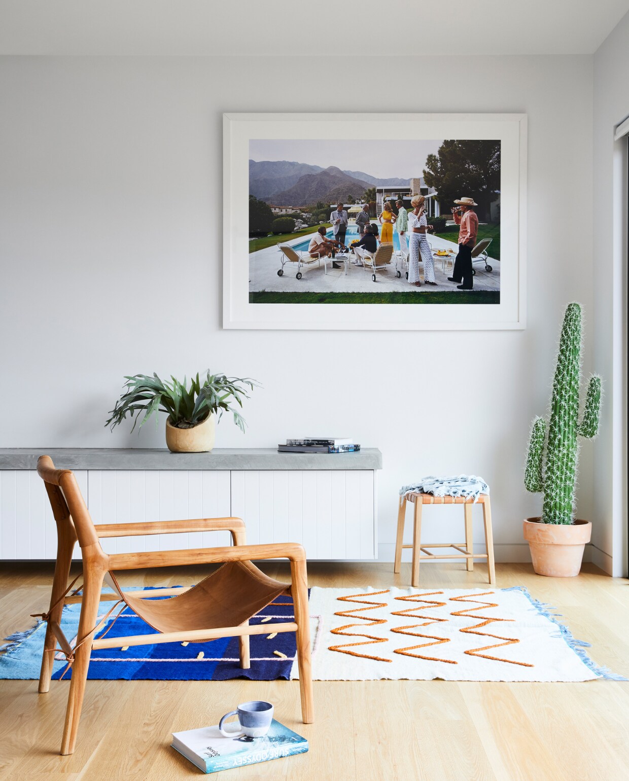 Kruk en vloerkleed Lrnce. Leren stoel Barnaby Lane. Kunstwerk Desert Houseparty van Slim Aarons. Overig onbekend. vtwonen special binnenkijken 07-2022 | productie Living Inside | styling Julia Green | fotografie Armelle Habib