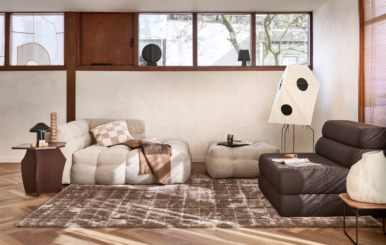 Vloerkleed Blocks in Warm brown, polyester en jute, 200x290 cm € 719,99. Ook verkrijgbaar in Warm white. M.m.v. loods5.nl (bank Fat Joe, hocker Fat Joe, waterglazen), studiohenk.nl (zitelement Layers, bruine bijzettafel), homestede.nl (houten kandelaar, ronde zwarte vaas, zwarte vaas, stenen dienblad, witte aardewerken vaas), vitra.com (papieren vloerlamp), vtwonen.nl/shop (zwarte tafellamp van Hay, plaid van Ferm Living), hm.com (geblokte kussenhoes), lennebelle.com (mok). Overig privébezit. vtwonen 06-2023 | productie Tanja Saarberg | styling Sanne Ketelaar | fotografie Sjoerd Eickmans | assistentie Evans van der Sluis