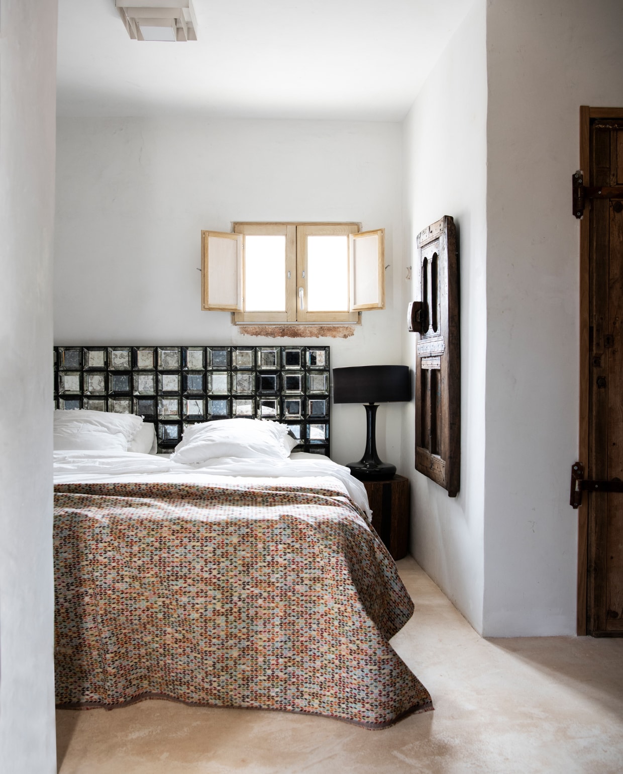 Bed Eurobed. Hoofdbord van glas Versmissen. Sprei gemaakt van stof van de markt. Beddengoed Zara Home. Lamp Now’s Home. Aan de muur een houten geitendeur uit Marokko. Cementvloer in crème via Calò Lenoci in Ceglie Messapica. vtwonen special binnenkijken 06-2022 | productie Insidehomepage | styling Marit Saladini Platjouw | fotografie Louis Lemaire