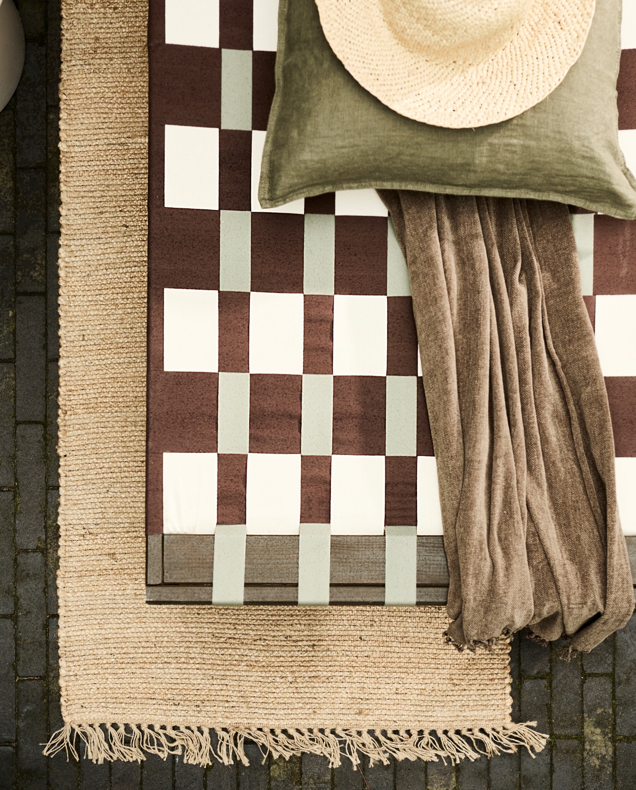 Grenenhouten frame daybed, 200x70x31,5-77 cm (lxbxh) € 67,99 (vidaxl.nl). Parasol van HKliving € 369,- (bijenkorf.nl). Grijze bloempot van Elho € 145,-, bijzettafel van HKliving € 249,- (vtwonen.nl/shop). Plaid € 24,99, kussen € 12,99, juten vloerkleed € 42,99 (hmhome.nl). Glazen karaf € 17,99, houten dienblad € 17,99, glas € 5,99 (zarahome.com). Overig privébezit. vtwonen 06-2023 | styling en uitvoering Sanne Ketelaar | fotografie Sjoerd Eickmans