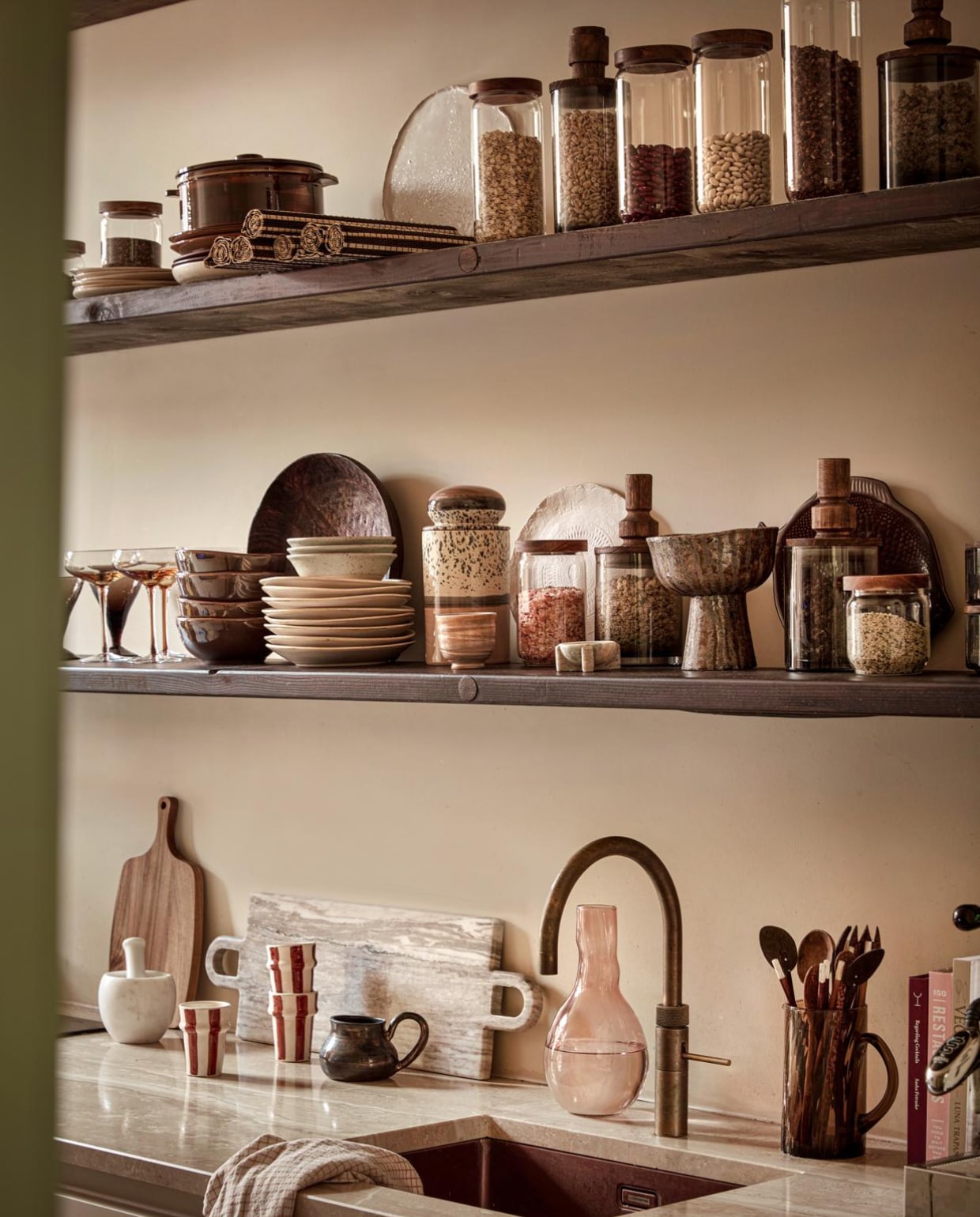 Bovenste plank: glazen voorraadpotten met houten deksel van Loods 5 Goods small € 3,95, medium € 4,95, bamboe placemats van Loods 5 Goods per 6 € 14,95, (loods5.nl). Stapel borden Wonki Ware, per stuk € 21,95 (loftloft.nl). Braadpan € 30,-, borden vanaf € 5,- (stijldepot73.nl). Wit handgemaakt dinerbord € 27,50 (lchandmadeceramics.nl). Glazen voorraadpotten met hoge greep € 29,55, met lage greep € 28,80 (nordal.com). Onderste plank: Bruine glazenper stuk € 5,- (loftloft.nl). Roze champagneglazen per stuk € 15,-(stijldepot73.nl). Donkerbruine schalen van Loods 5 Goods per 6 € 41,95, beige borden van Loods 5 Goods per 6 € 47,95, keramieken voorraadpot HKliving € 44,95, glazen voorraadpot met houten deksel van Loods 5 Goods medium € 4,95, small € 3,95 (loods5.nl). Gespikkelde schaaltjes per stuk € 18,17, glazen voorraadpot met lage greep € 28,80, kleine natuurstenen schaal € 24,25, glazen voorraadpot met hoge greep € 29,55 (nordal.com). Mok privébezit. Wit handgemaakt dinerbord € 27,50 (lchandmadeceramics.nl). Keramieken schaal op voet € 95,-(@studio.cherrymoon). Visvormig bord € 19,95 (stijldepot73.nl).Op het aanrecht: Houten plank € 9,95 (vita32.nl). Natuurstenen vijzel € 50,75, natuurstenen plank € 170,45 (nordal.com). Gestreepte mokken per stuk € 8,95 (loftloft.nl). Donkerbruine mok € 45,- (@klyvanmy). Roze glazen vaas € 19,95 (urbannatureculture.com). Geruite theedoek van Loods 5 Goods per 3 € 12,95, bruine glazen karaf € 12,95, kookboeken vanaf € 26,99 (loods5.nl). Overig privébezit. vtwonen 2022-10 | styling Demelza Krens | fotografie Peggy Janssen