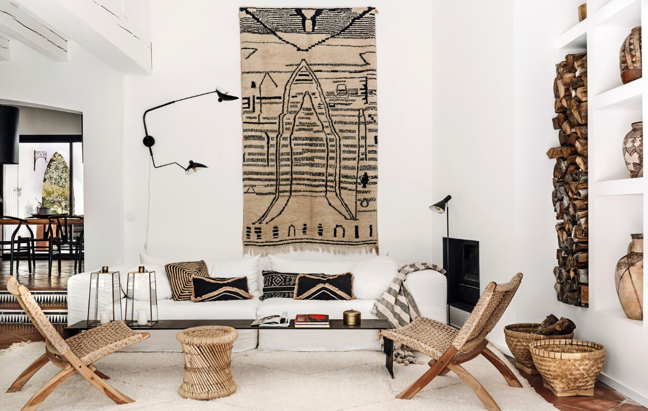 Wandkleed uit Marokko, wandlamp Serge Mouille. Vergelijkbare producten: bamboe bijzettafel Ganon van Sklum, vloerkleed Beni Ouarain van Rozenkelim, plaid met franjes Bloomingville, kussens Xenos, wandlamp van Am.Pm via La Redoute, rieten fauteuil Grignoon van Kave Home. Overig onbekend. vtwonen 06-2023 | productie Taverne Agency | styling Mari Strenghielm | fotografie Anna Malmberg