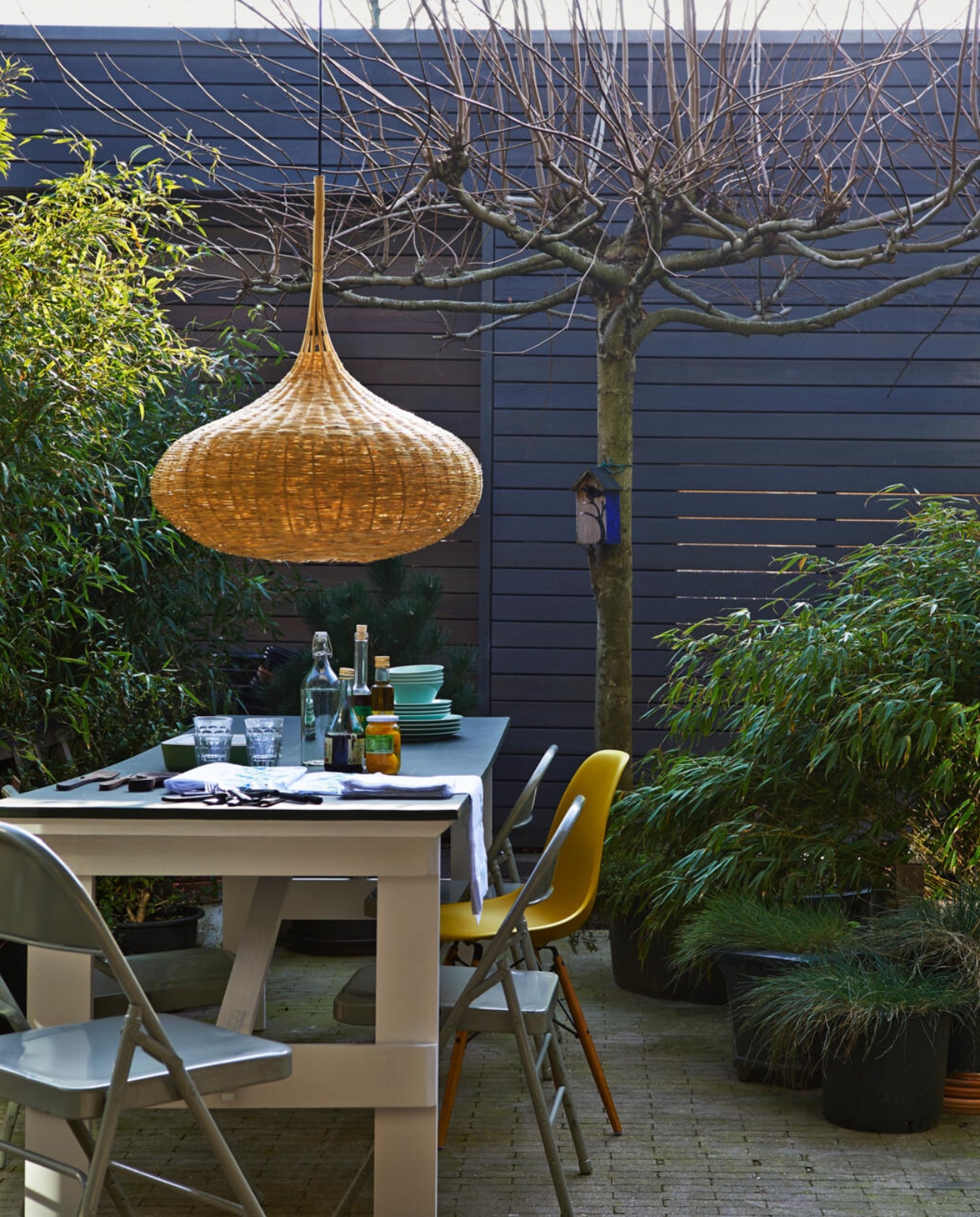 Grijze klapstoelen, tafel inklapbaar, afgewerkt met groene schoolbordverf (Combitex). Mosterdgele stoel, ontwerp Eames (Loods 5). Rieten hanglamp, tafelkleed geborduurd en servetten (Household Hardware). Celadonkleurig servies 12-delige set € 12,95, groene schaal (Ikea). Diverse bamboe (Kwekerij De Limieten). vtwonen 05-2014 | styling Fietje Bruijn | fotografie Jeroen van der Spek