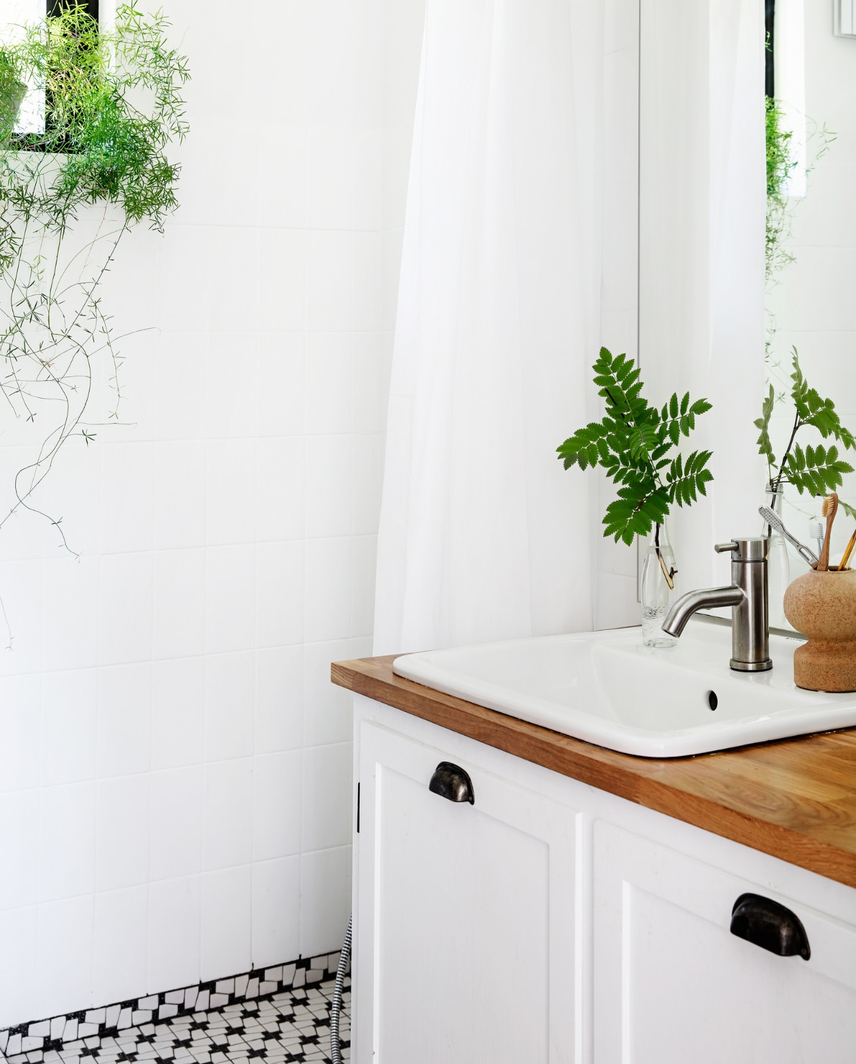 De kleine badkamer zat al in het huis en kreeg een make-over: de wandtegels zijn geschilderd en er kwam een vintage wastafel en houten wastafelblad. vtwonen special binnenkijken 06-2022 | productie Living Inside | styling Rikke Graff Juel | fotografie Christina Kayser O.