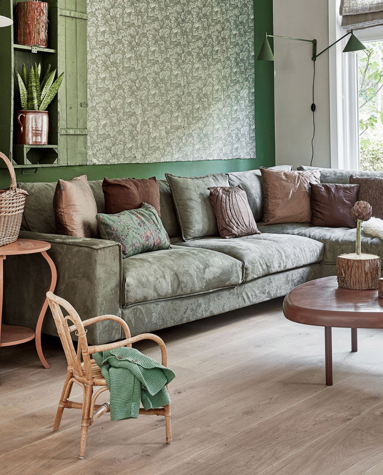Verf Full Jade van Flexa Pure, extra brede wit geoliede planken Floer. Bank Goossens wonen &amp; slapen, kussens mix van kringloop en tuincentrum. Salontafel vintage met poten van een bouwmarkt. Groene lampen HKliving. Bijzettafel, rieten mand en kandelaar kringloop. Kinderstoel vintage. Witte lamp Lumalano. Boomstammen zelfgemaakt, vitrinekast zelfgemaakt van een oude munitiekist. Bloempot Vintage Twist 66 en vouwgordijn stof Mees Karwei. vwonen 2020 bk | Fotografie Peggy Janssen