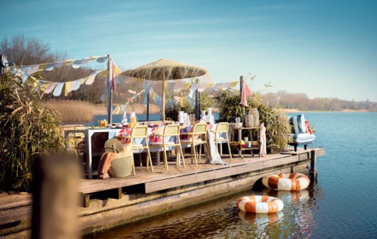 Vlaggen gemaakt van oude dekbedovertrekken, lange tafel gemaakt door Combitex, stalen poten en houten bovenblad, prijs op aanvraag (com-anders.nl). Stoelen Toní Armchair van Fatboy, set van 2, waterglazen Pure van Serax, 0,2 liter, set van 4, karaf Pure van Serax op trolley, 1,2 liter, blauwe glazen Terres de Rêves van Serax in trolley, 0,34 liter, blauwe borden Pure van Serax, 9-delig, okerkleurige bijzettafel Filippo van Serax, 40x46 cm (Øxh), witte vazen Billy van Serax, 27 cm (h), 30 cm (h), 37 cm (h), 31 cm (h), waterdispenser van Serax, 10 liter, zilverkleurig bestek Base van Serax, 24-delig, blauw-wit gestreepte fauteuils Paletti Seat van Fatboy, grote rotan grote lantaarn Ferdi van Bloomingville, (vtwonen.nl/shop). Zwemband Celine van Petites Pommes, zwemband Sally van Petites Pommes, bamboe trolley, waaier in tas maat M, tas Capazo Maya L, gele karaf Amber, gevlochten parasol uit Marokko, 200x240 cm (Øxh) (couleurlocale.eu). Roze ontbijtborden, 17 cm (Ø), set van 12, oranje handdoek, oranje glazen karaf, gele theeglazen, set van 4 (sissy-boy.com). Blauw-wit geblokt wollen plaid, roze linnen kussen op bank, 40x60 cm, geel-wit gestreept kussen, 50x50 cm, oranje-wit geruit kussen, 50x50 cm, blauwe kommen, roze-witte theedoeken geknoopt als vlaggen, set van 3, klein zeegras windlicht op trolley, lopers, blauw-wit tafelkleed, 140x180 cm, roze linnen servet, 45x45 cm, set van 2, keramieken vergiet op trolley (hm.com). Mand met citroenen (dekringloper.nl). Geel-wit gestreepte stoelkussens (fatboy.com). Donkerroze schaal in trolley, prijs op aanvraag (zarahome.com). Takken, prijs op aanvraag (waterdrinker.nl). Overig privébezit. vtwonen 07-2023 | styling Liza Wassenaar | fotografie Sjoerd Eickmans