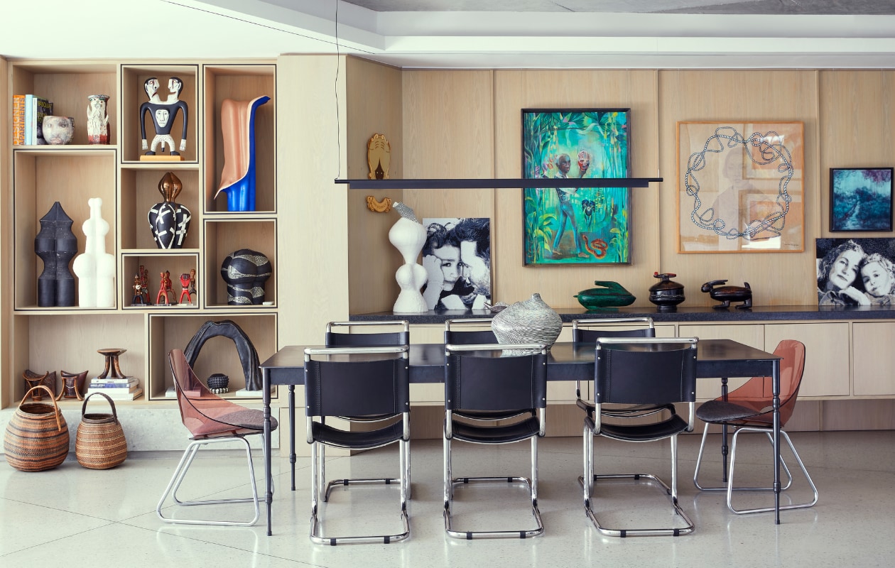 Eettafel Gregor Jenkin. Zwarte stoelen in opdracht gemaakt, roze stoelen vintage. Keramiek (zwart en wit, blauw-roze) in de kast en op tafel van Martine zelf. Houten beeld tweekoppige man Norman Catherine. Gemarmerd beeld Patsy Groll. Zwart-geel wandkunstwerk Brett Murray. Schilderijen v.l.n.r.: Olaf Hajek, Mariëtte Bergh en Syndi Kahn. Overig onbekend. vtwonen special binnenkijken 06-2022 | productie Bureaux | styling Sven Alberding | fotografie Elsa Young