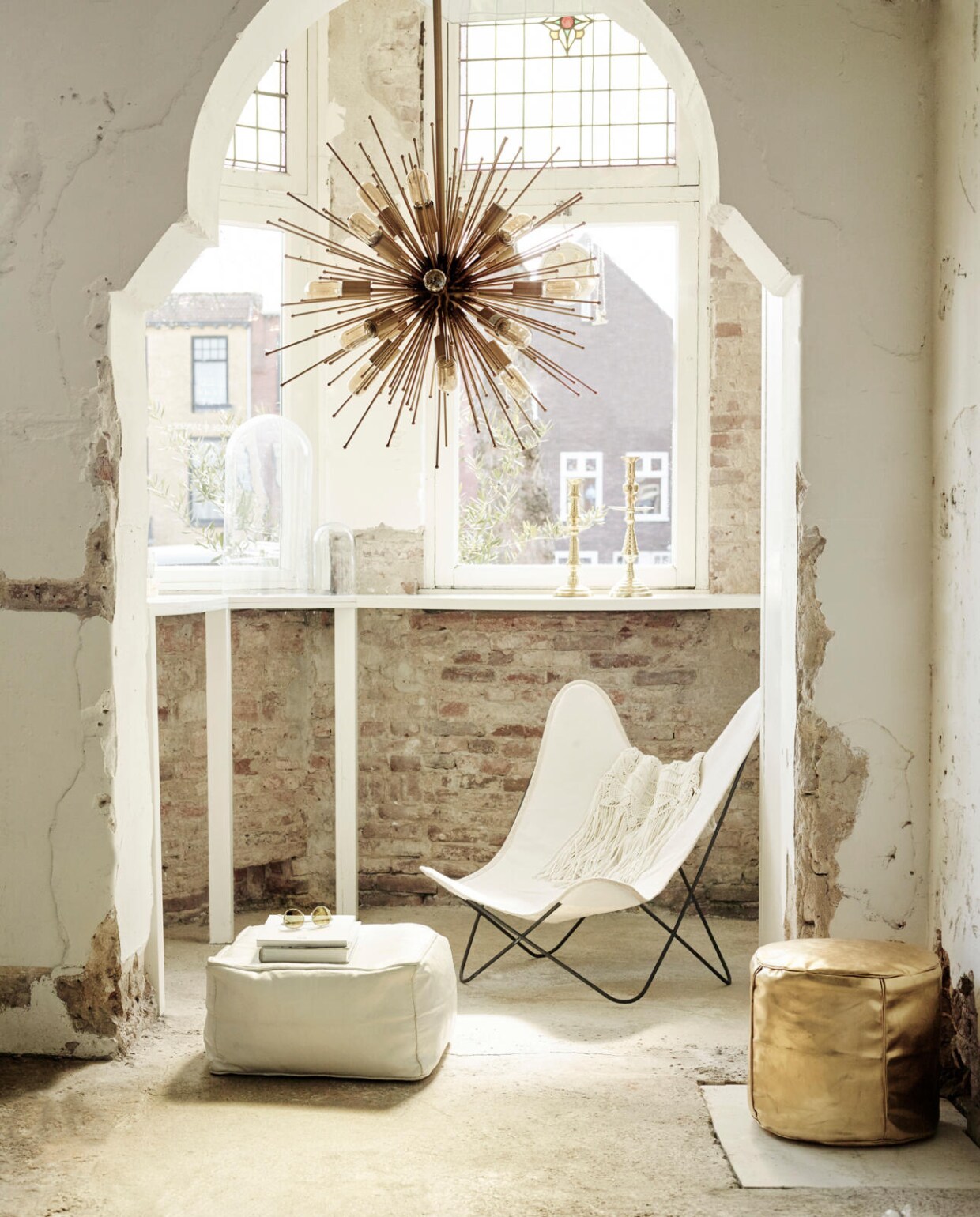 Lamp van Madam Stoltz (Deens). Vlinderstoel, witte leren poef, goudkleurige poef, goudkleurige kandelaars, witte metalen stoel (Household Hardware). Vestje met franjes (H&amp;M). Bril met goudkleurige spiegeling (Saraghina Eyewear). vtwonen 07-2016 | fotografie Tjitske van Leeuwen | styling Marianne Luning