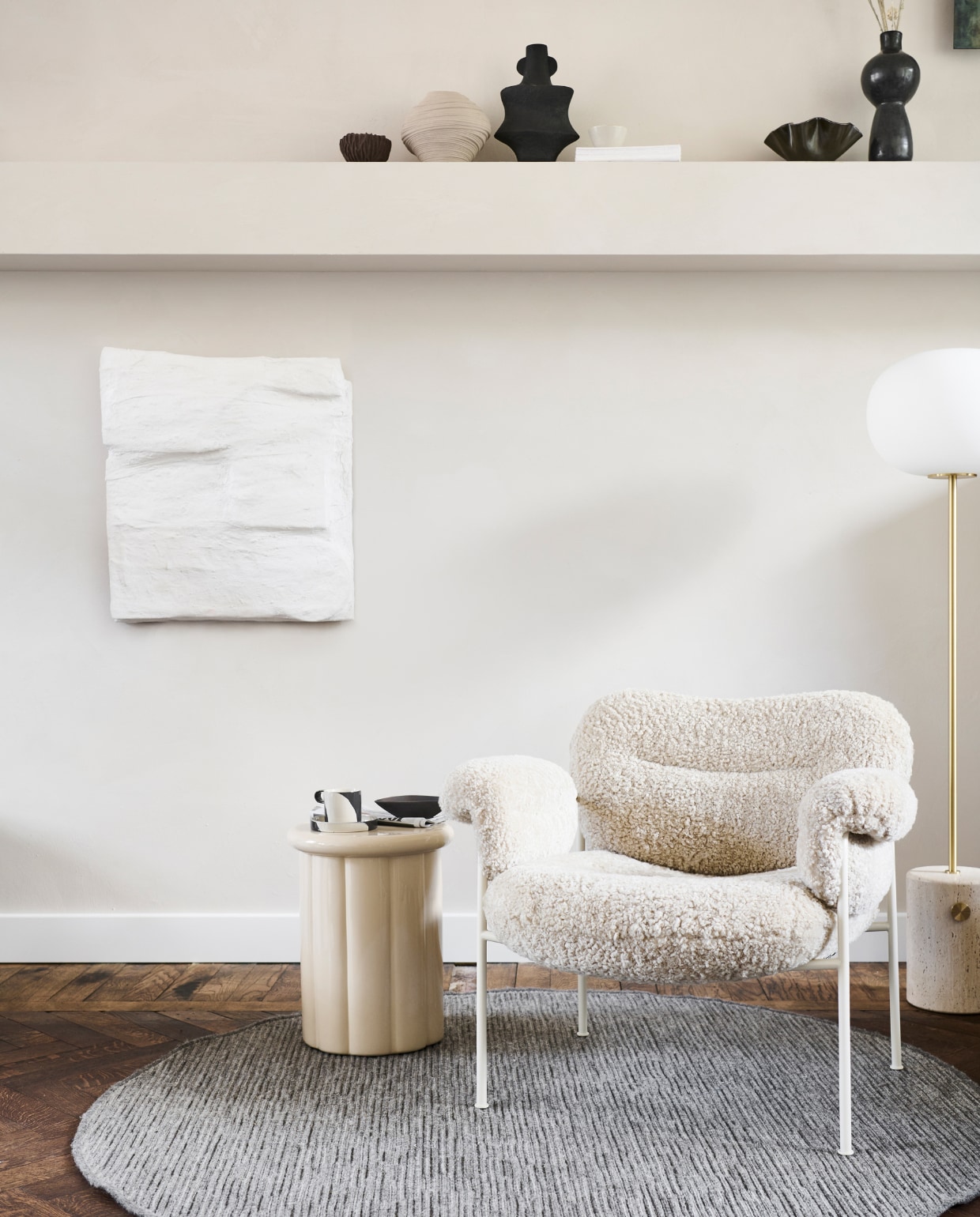 Wollen vloerkleed Nature Cord in kleur antraciet melé, 160 cm (Ø) € 299,99. M.m.v. polspotten.nl (bijzettafel), vtwonen.nl (kop-en-schotel van Ferm Living), homestede.nl (fauteuil), designtales.nl (vloerlamp, zwarte schaal), instagram.com/ansdekruyf (schilderij van Ans de Kruyf), hm.com (bruine kom, grijze vaas, zwarte matte vaas), letoile.store (witte kom), paviljoennoord.com (zwarte vaas). Overig privébezit. vtwonen special 12-2022 | productie Tanja Saarberg | styling Danielle Verheul | fotografie Sjoerd Eickmans