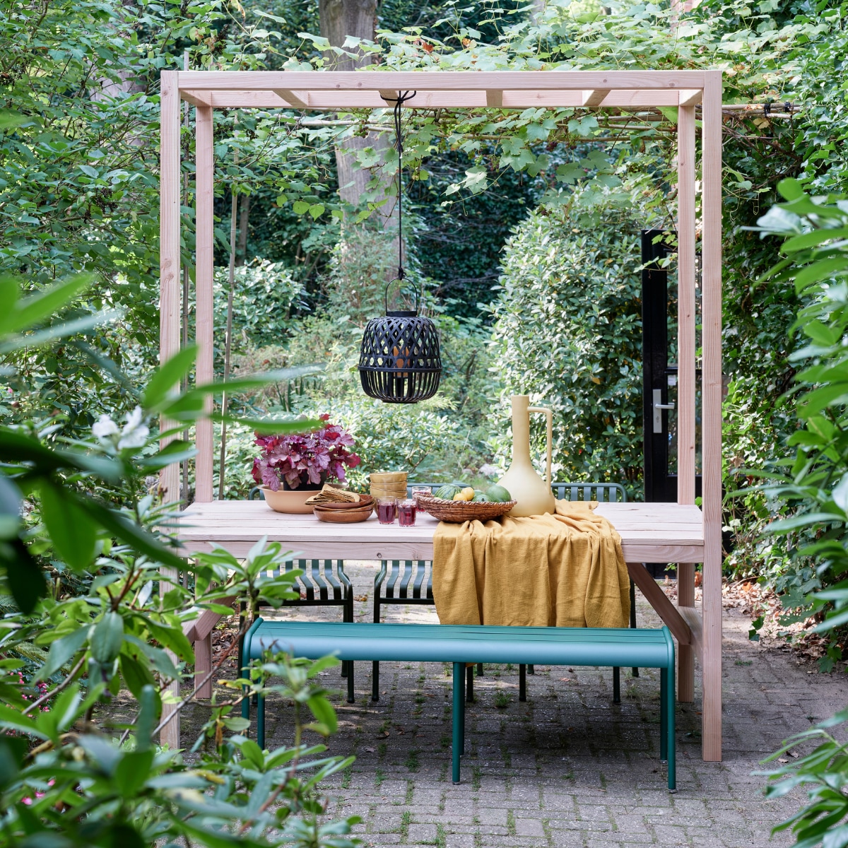 Foto’s deze en vorige pagina: tuinbank Luxembourg van Fermob, stoelen Palisade Chair van Hay (vtwonen.nl). Tafelkleed van okergele stof (patickkarteris.nl). Hoge vaas, diepe borden Glaze (kwantum.nl). Bamboe lantaarn, schaaltjes, schaal (intratuin.nl). Sisal schaal (hm.com). Linnen servetten (hm.com).
 vtwonen tuin special 5-2022 | styling Moniek Visser | fotografie Sven Benjamins