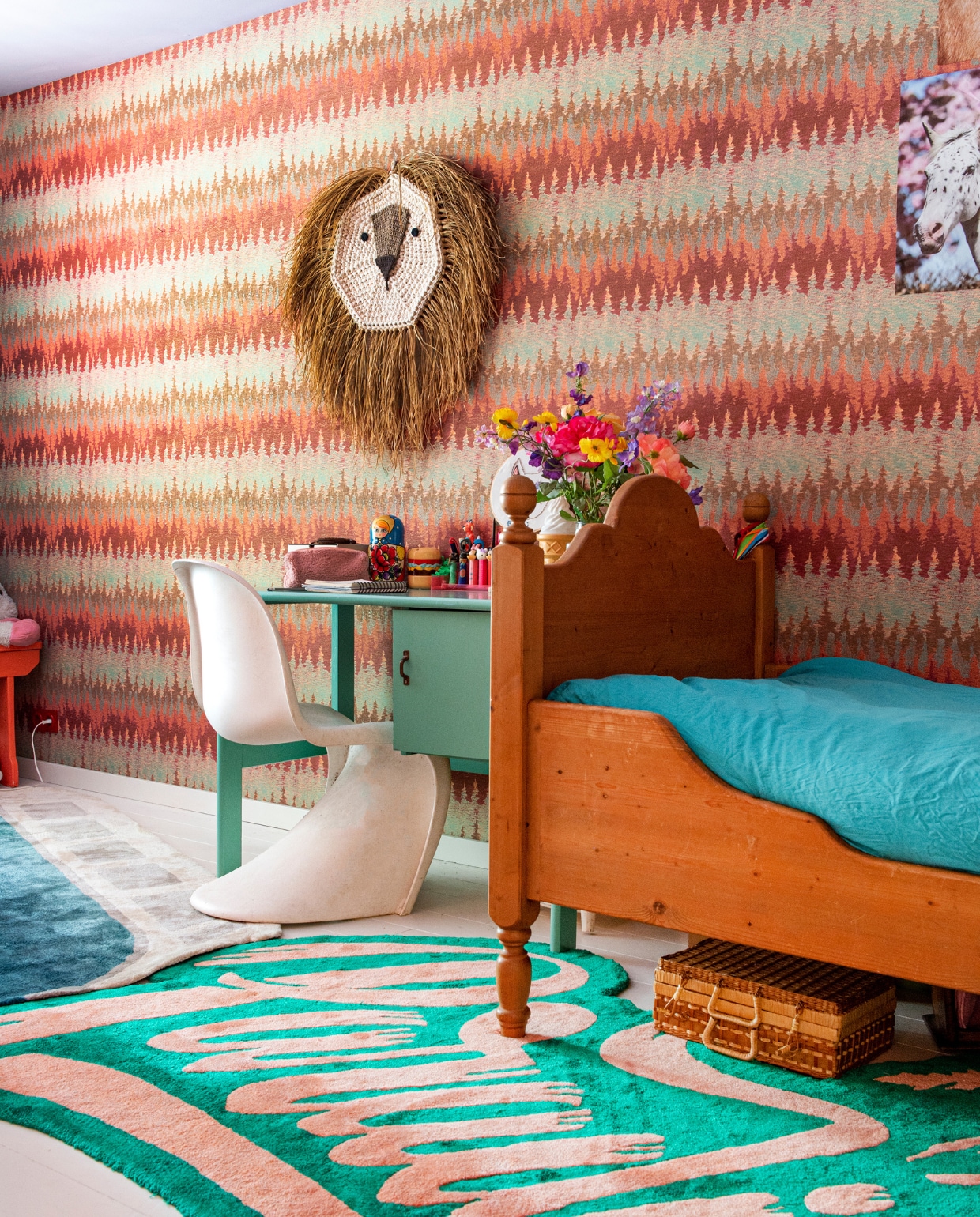 Behang Ferm Living, bureau Marktplaats, stoel Panton van Vitra, vloerkleden Studio Vacay. Bed en rieten koffer uit oude kinderkamer van Bettina. Leeuwenkop souvenir uit Spanje. vtwonen 07-2023 | productie De Binnenkijkers | styling Jeske Weel | fotografie Caroline Coehorst