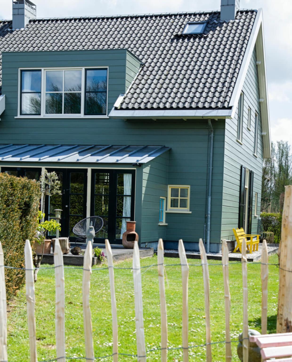 Het huis is aan de buitenkant afgetimmerd met hout, maar heeft een betonnen constructie. De kleur is bepaald door de monumentencommissie en mag niet worden veranderd. Tuinbankje geschilderd in Nancy’s Blushes van Farrow &amp; Ball. vtwonen 07-2021 | styling Ilona Jongepier | fotografie Dana van Leeuwen