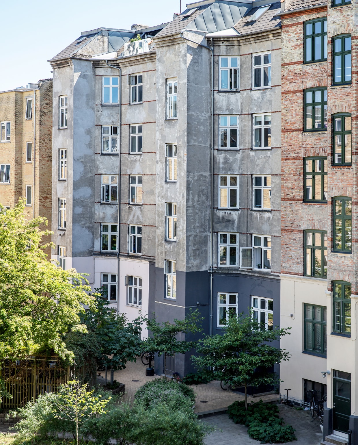 Voor het appartementencomplex bevindt zich een onlangs opgeknapt plein vol groen. vtwonen special binnenkijken 03-2023 | productie Living Inside | styling Rikke Graff Juel | fotografie Christina Kayser Onsgaard
