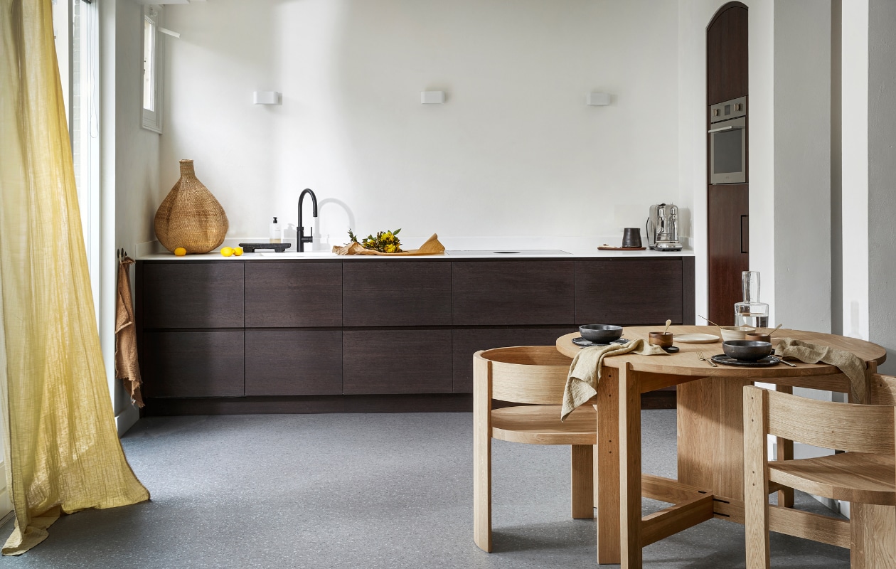 Novilon vloer in Graniet, per m_ _ 36,75 (excl. installatie). M.m.v. letoile.store (eikenhouten eettafel en stoelen van Kristina Dam, linnen servetten, mokken met schotels van Serax, keramieken servies), justanothershop.nl (knoflookvormige mand, snijplank, zwarte kan), lidor.nl (gordijn van Numero 74). Overig priv_bezit. vtwonen 07-2023 | productie Tanja Saarberg | styling Marlies Does | fotografie Peggy Janssen | assistentie Lisa Weel