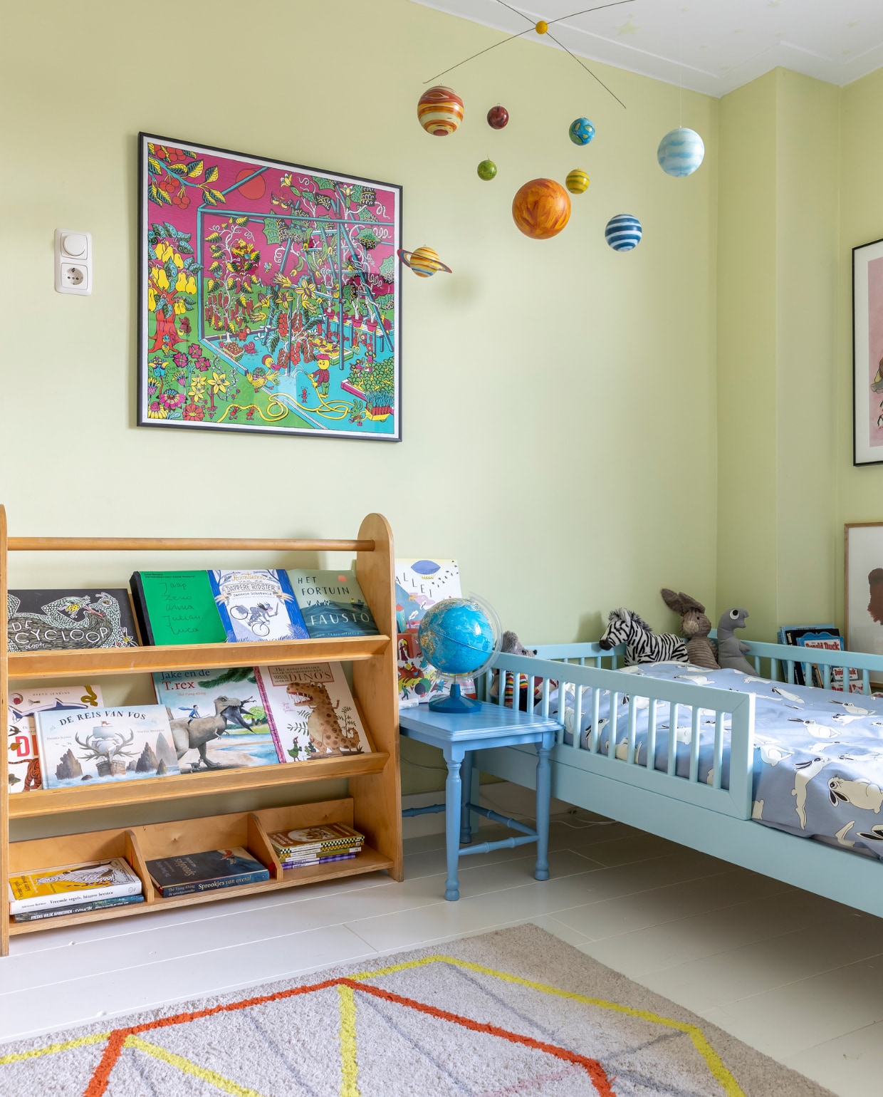 Muurverf H7.13.80 van Sikkens, houten vloer wit geschilderd, mobile Marktplaats, boekenkast Educo, bijzettafel gemaakt door Hendrikjes opa, bed Tommy van Petit Puk, beddengoed Mini Rodini, wereldbol vintage, kleed Ikea, zeefdruk Suze Alba, zebra Wwf, konijn Jellycat, dino Discodip. vtwonen 07-2023 | fotografie Henny van Belkom
