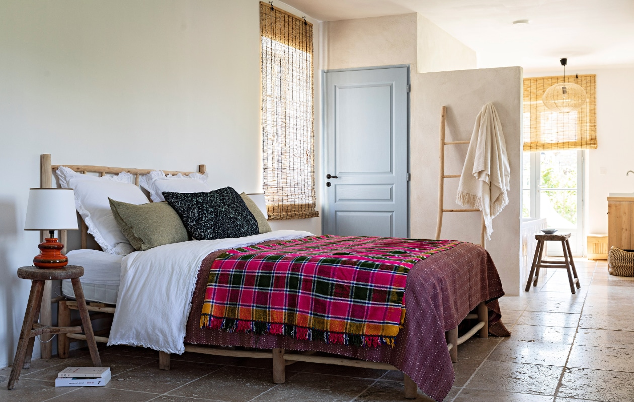 Bed op maat laten maken in Marrakech, dekbedovertrek en hanglamp uit Marrakech, bijzettafel Atmosphère d’Ailleurs, tafellamp rommel-markt, ladder Marché de M. Vergelijkbare bamboe rolgordijnen Kwantum. Vergelijkbare blauwe verf op deur: Borrowed Light van Farrow &amp; Ball. Overig onbekend. vtwonen 07-2023 | fotografie Yann Deret